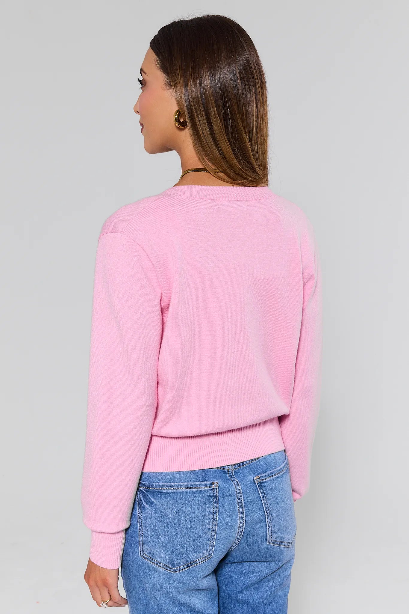 Person wearing a Sarah Light Pink Button Up Cardigan and blue jeans on a plain background