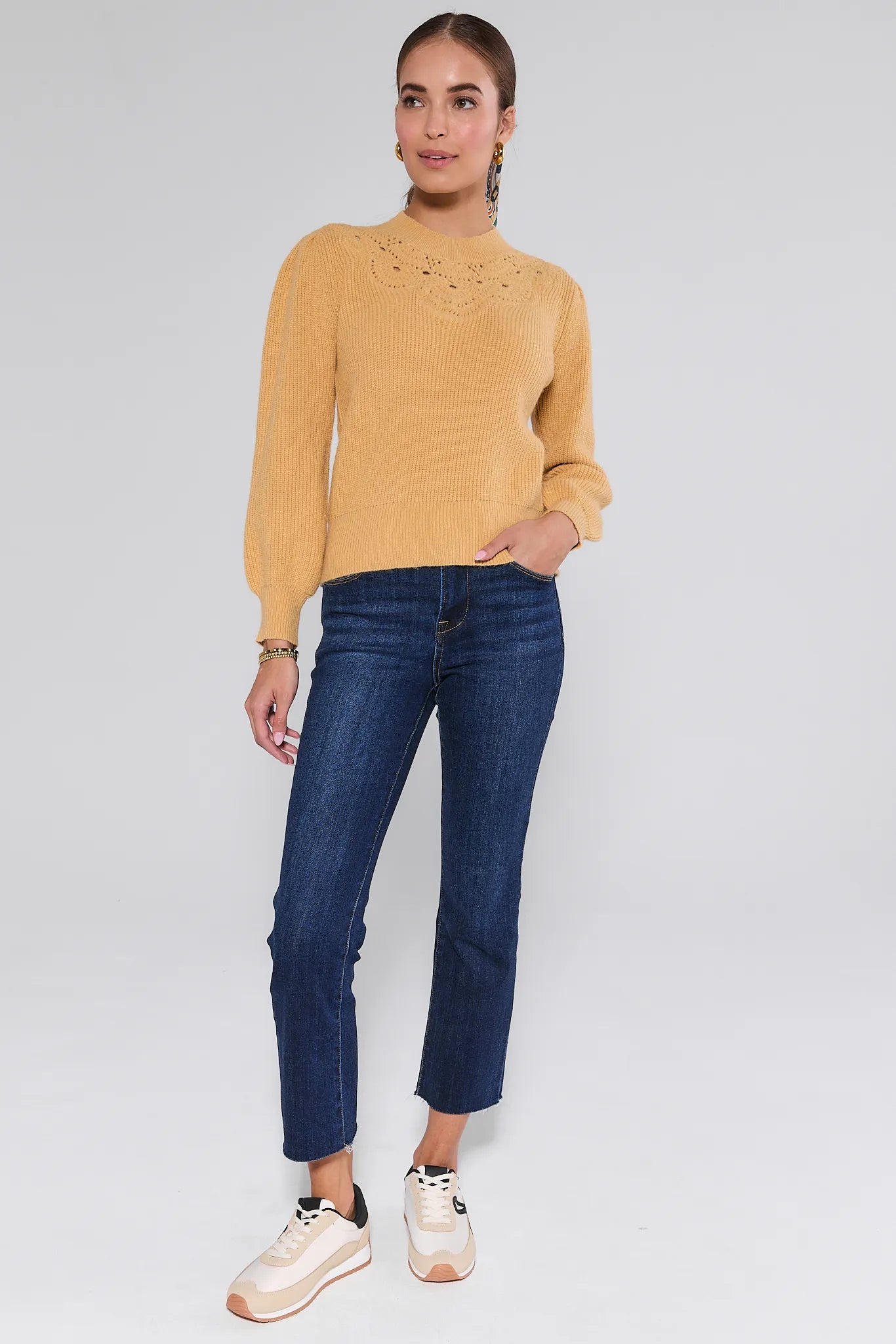 Woman wearing a yellow Dixie Sweater
 and blue jeans on a white background