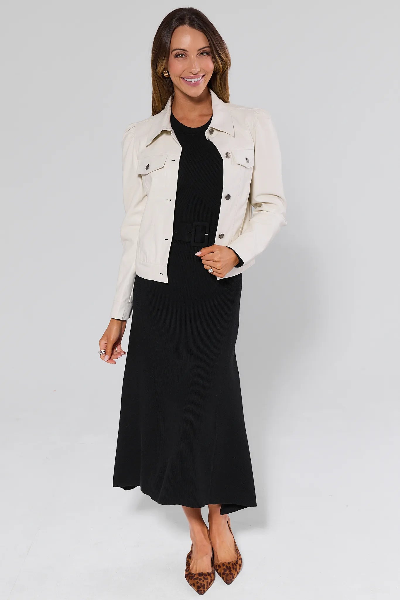 Woman wearing a white denim jacket over a Massey Black Knit Midi Dress on a plain background