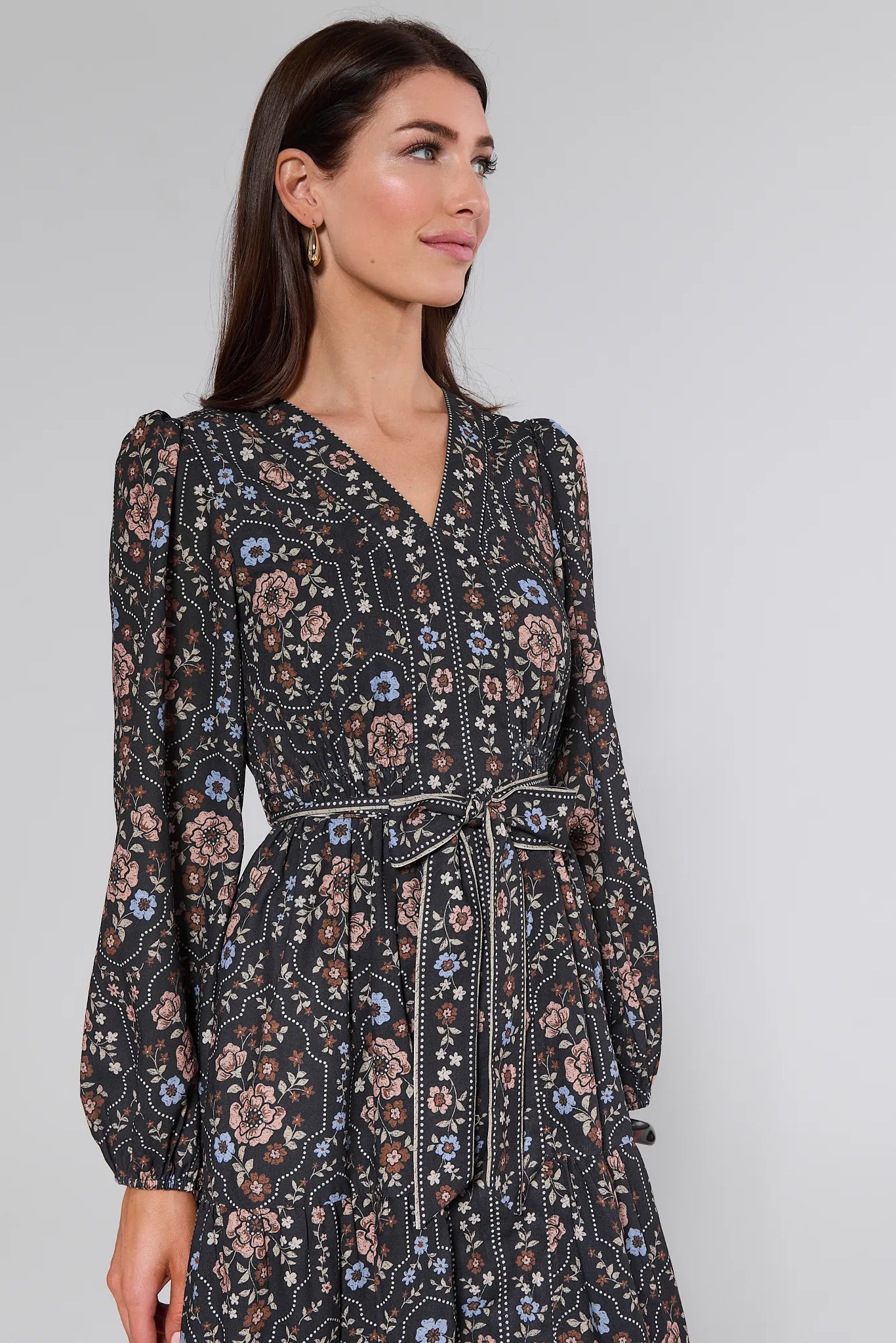 Woman wearing a floral Bowen Dress against a plain background