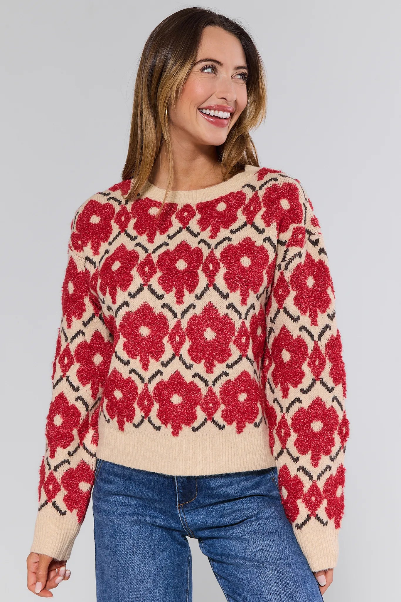 Woman wearing a red floral patterned Brynn Sweater against a plain background