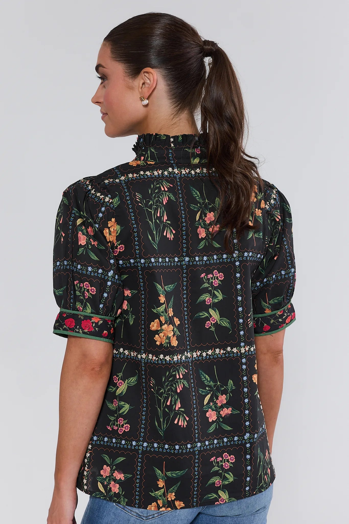 Woman wearing a black floral embroidered Adele Top on a white background