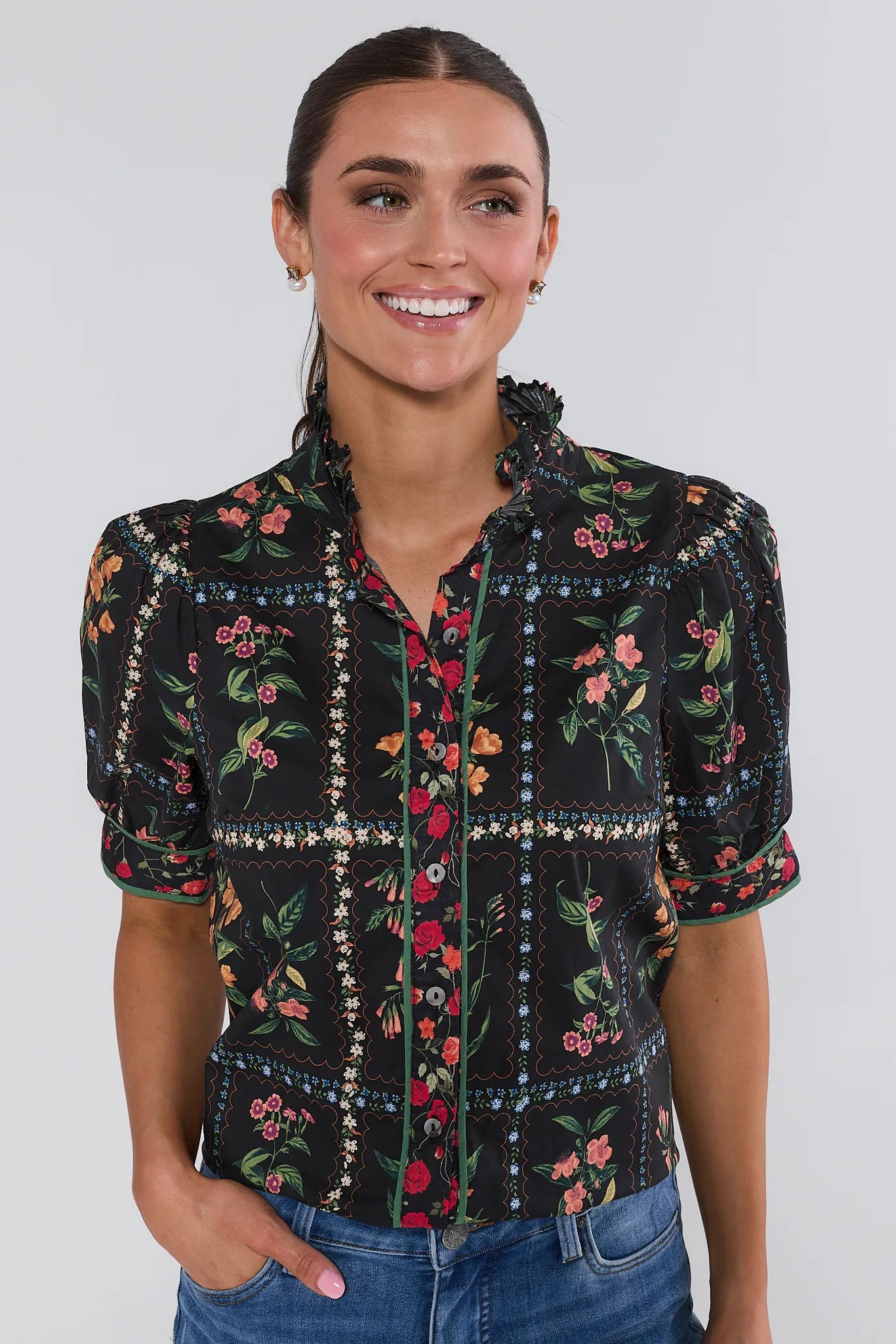 Woman wearing a black floral patterned Adele Top against a plain background