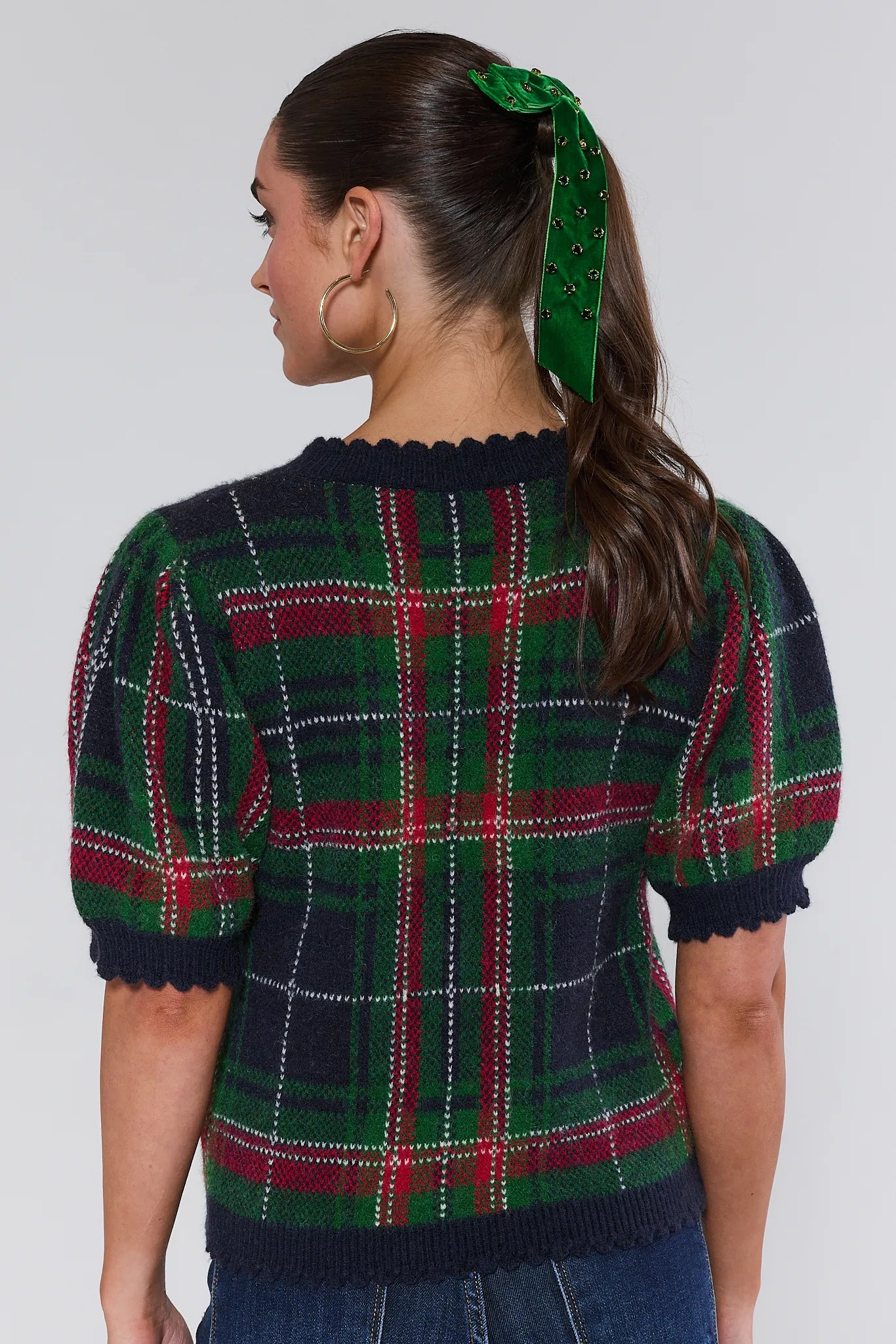 Woman wearing a plaid sweater with a green headband against a white background