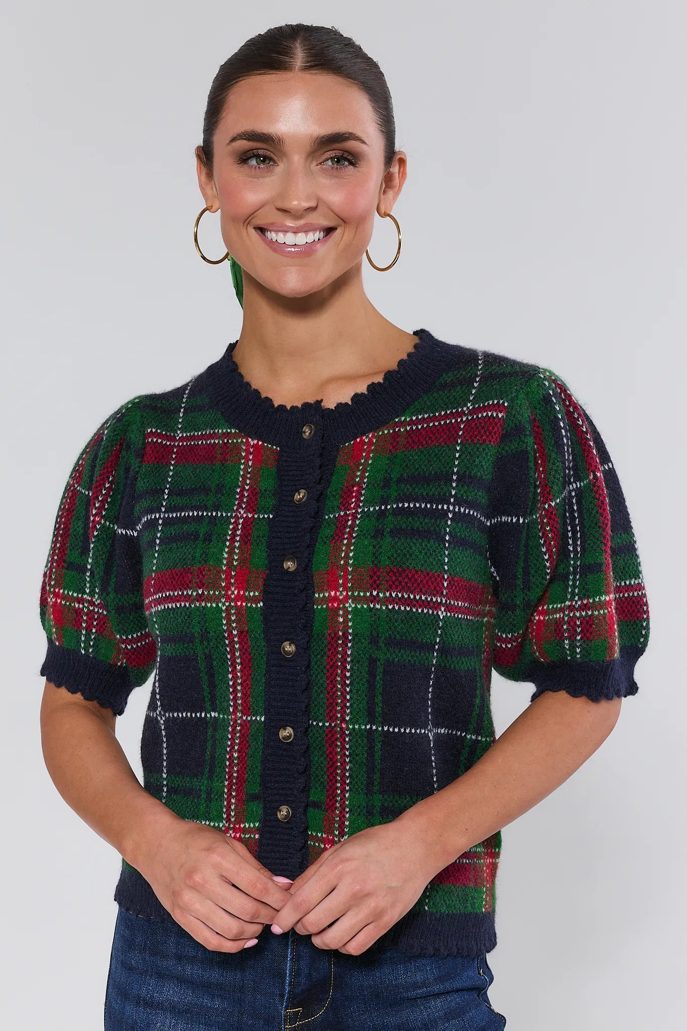 Woman wearing a plaid sweater with a plain background
