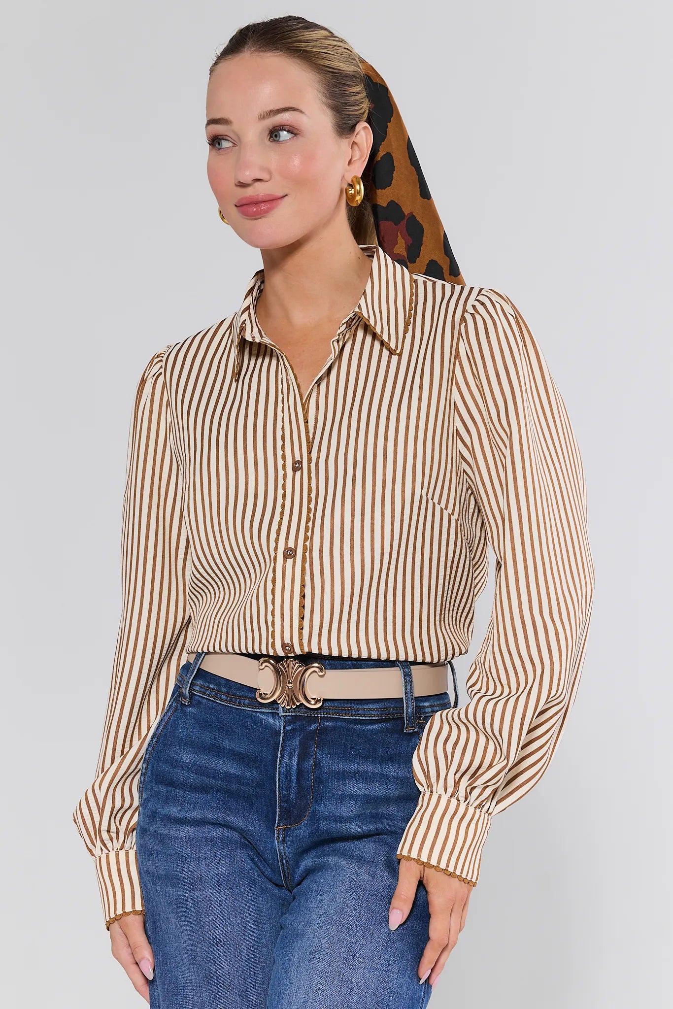 Woman wearing a striped Levi Top and jeans with a patterned headscarf on a plain background