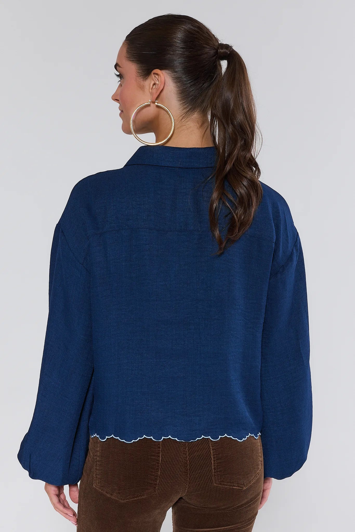 Woman wearing a blue Micah Top with a white trim on a plain background