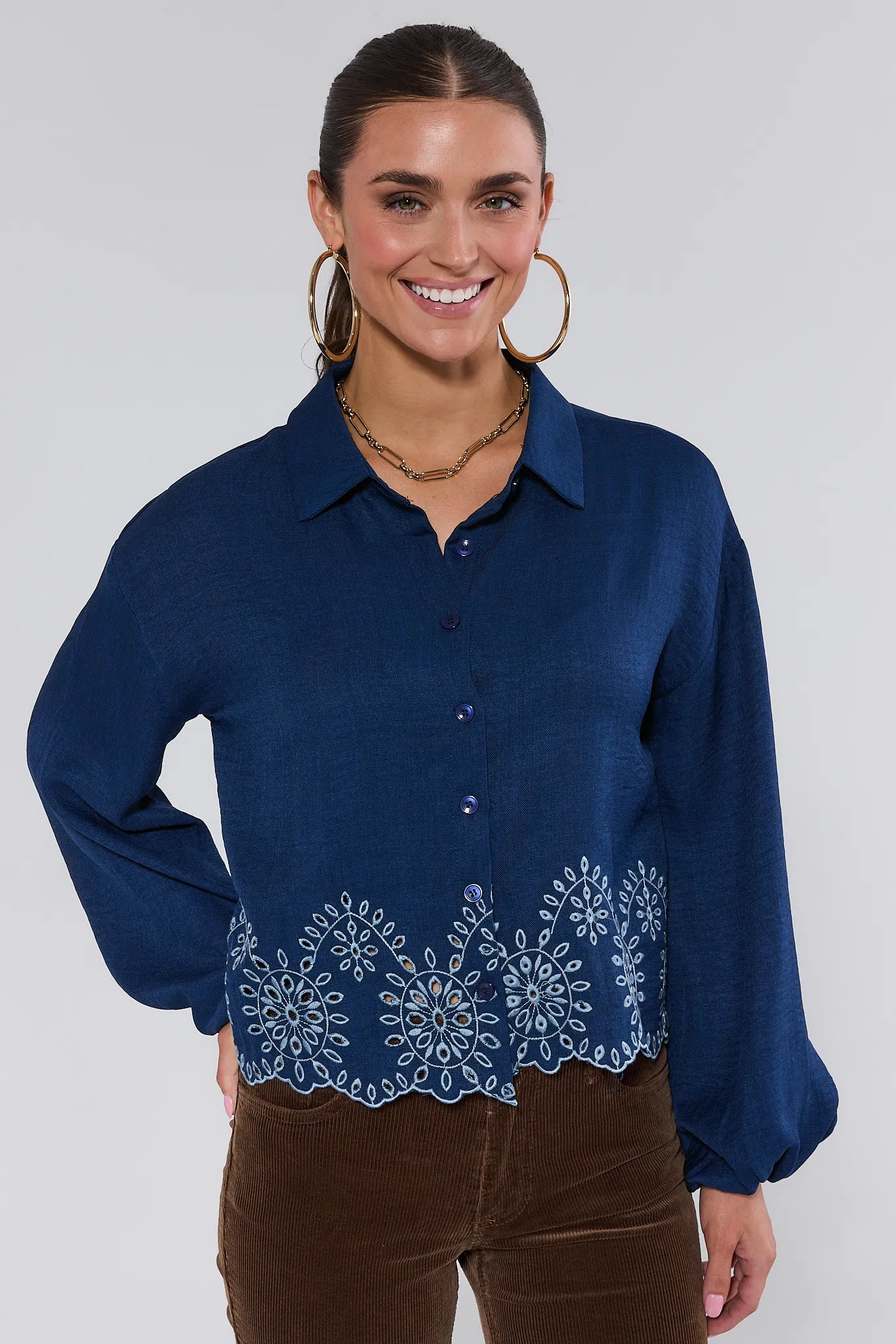 Woman wearing a blue Micah Top with lace details on a white background
