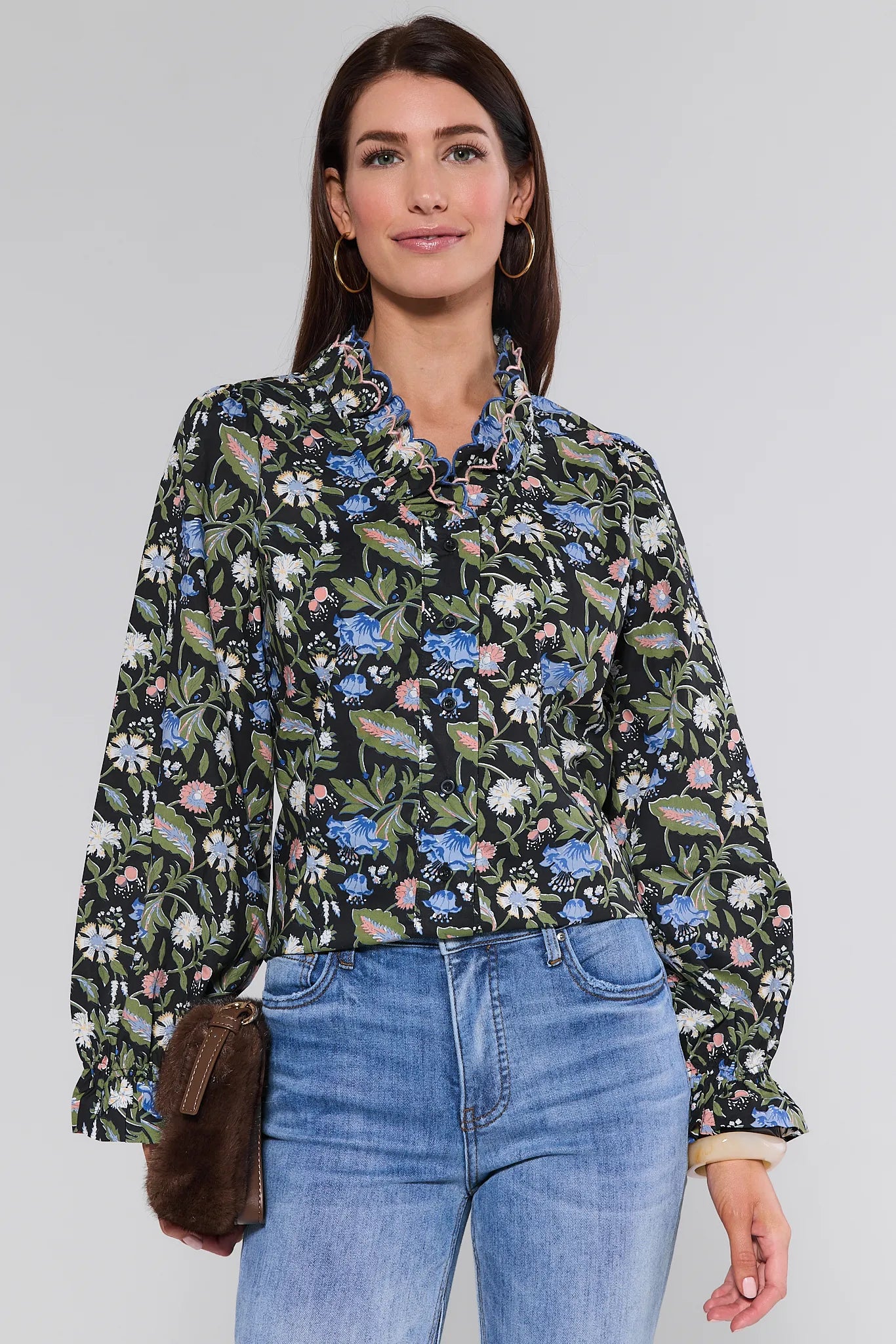 Woman wearing a floral Florence Top and blue jeans against a plain background