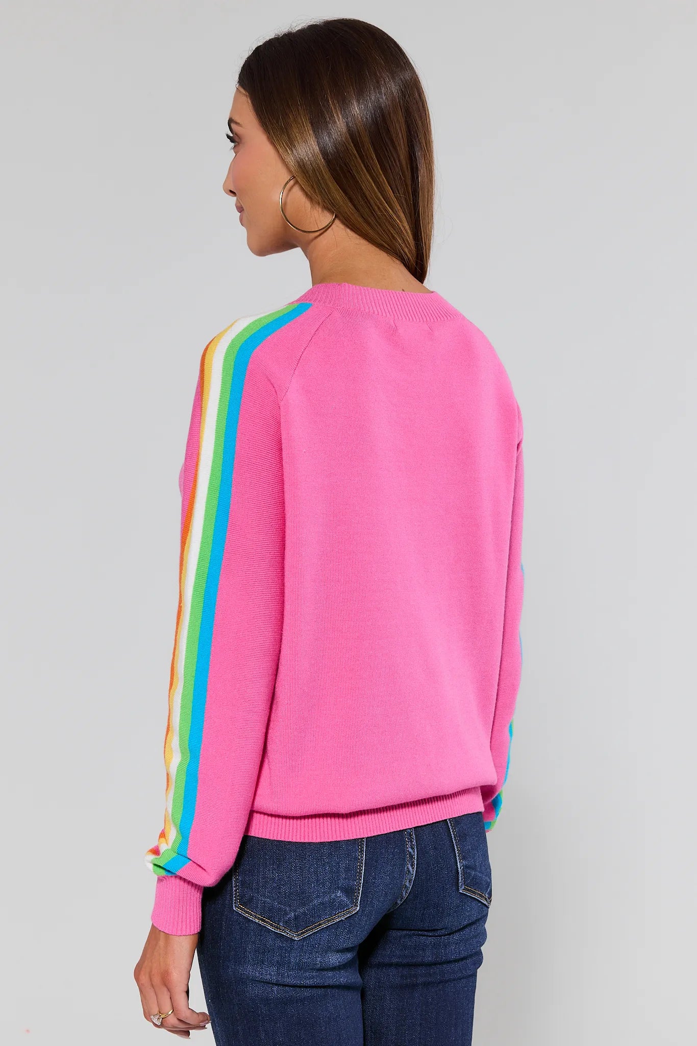 Woman wearing a pink sweater with rainbow sleeves against a plain background Khloe Pink Striped Sleeve Sweater