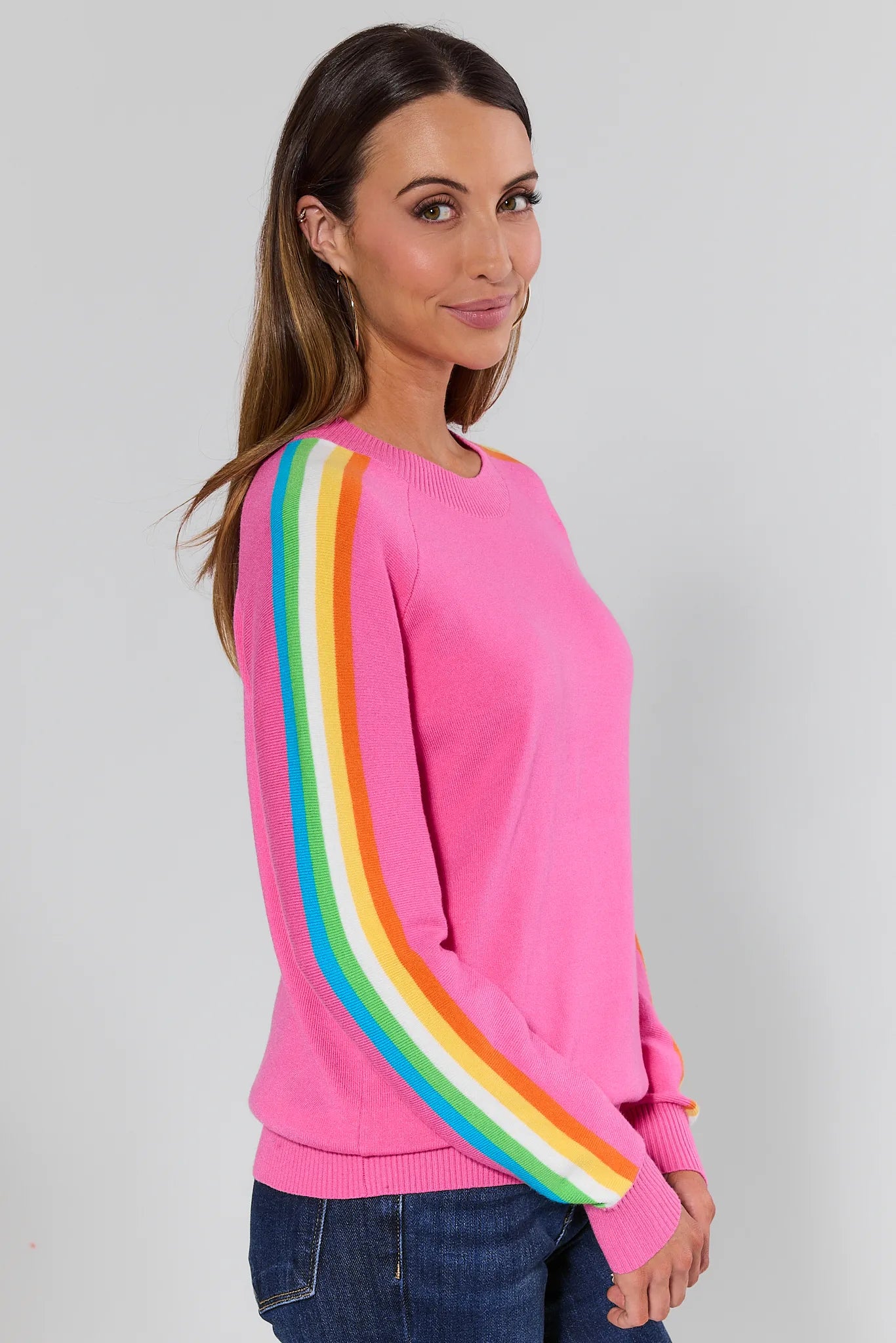 Woman wearing a pink sweater with rainbow sleeves against a plain background Khloe Pink Striped Sleeve Sweater