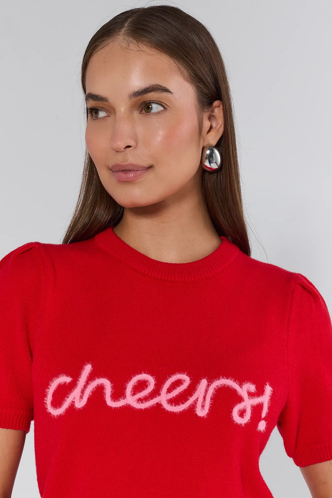 Woman wearing a red sweater with 'cheers' text on a plain background