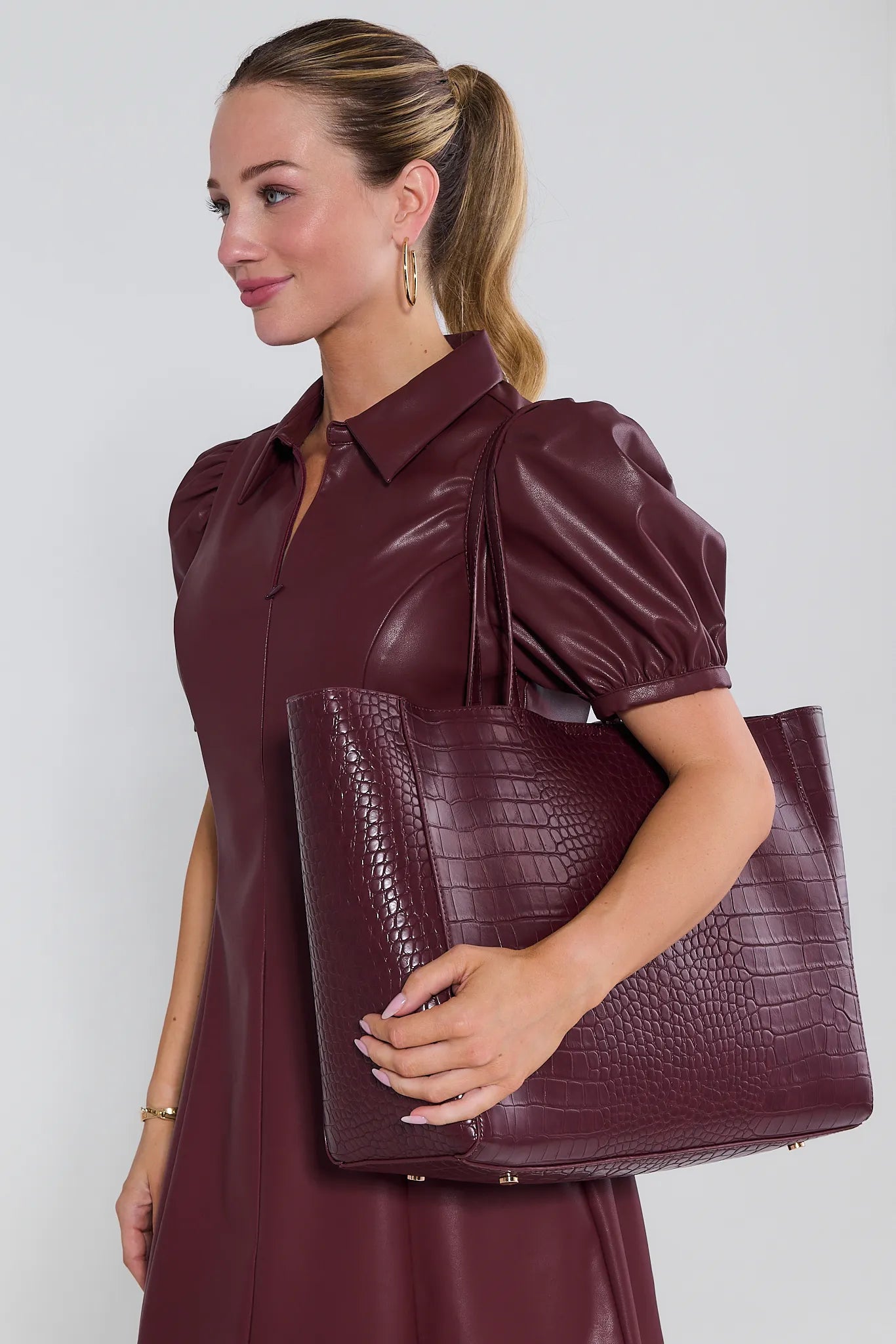 Woman holding a maroon leather Tiffany Bag against a white background