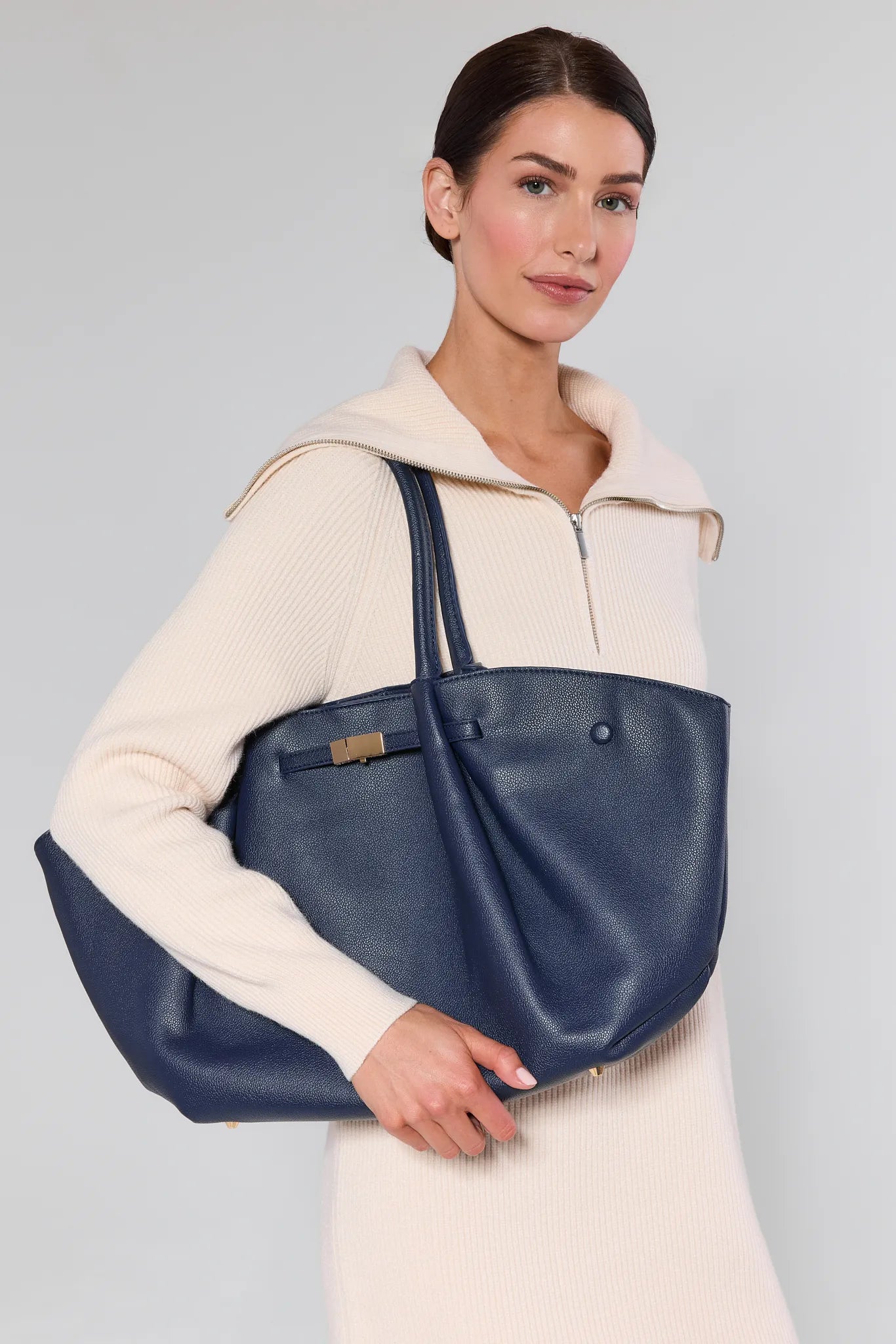Woman holding a blue tote bag against a plain background Kyra Navy Faux Leather Bag