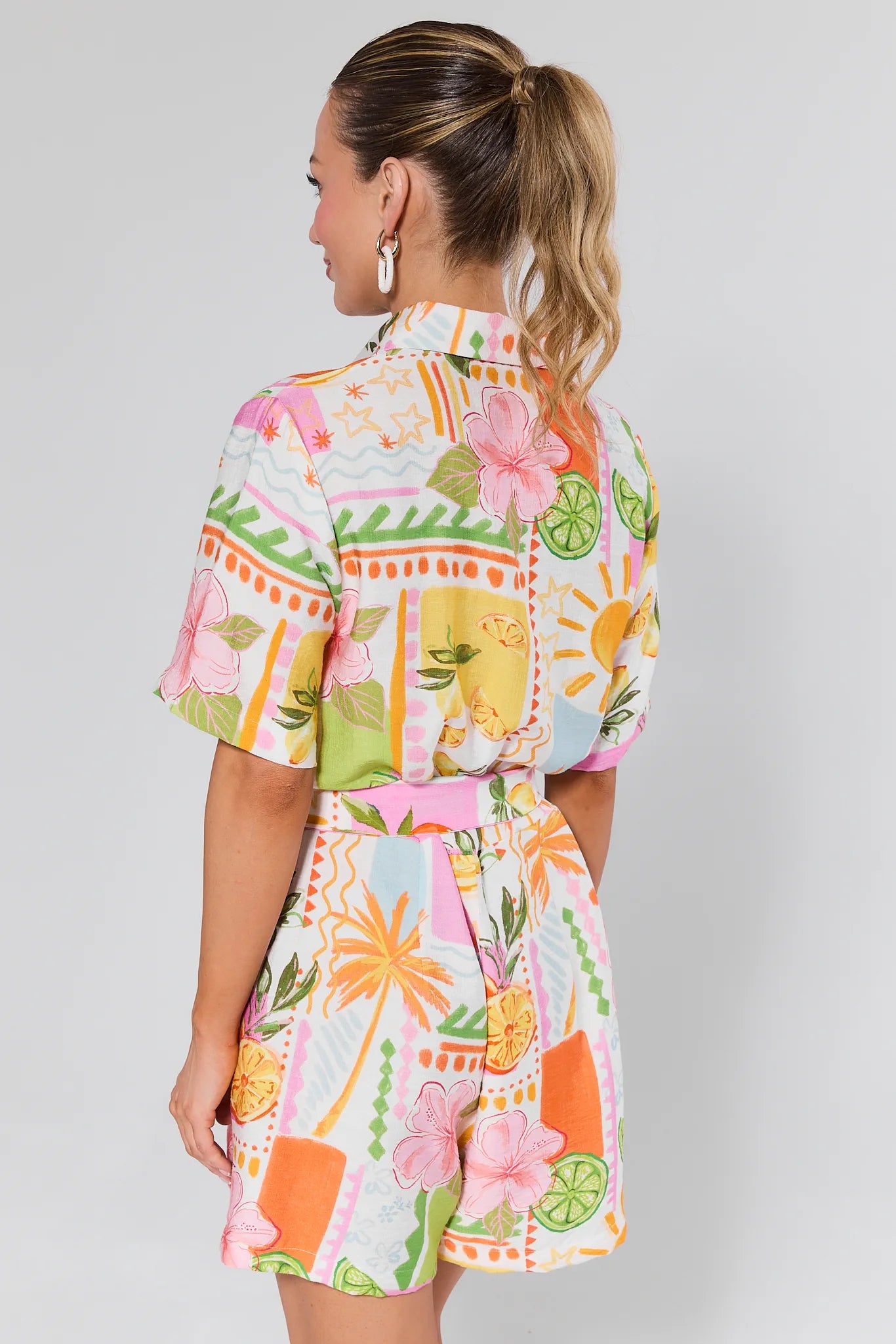 Woman wearing a colorful Saylor Printed Button Up Romper on a plain background