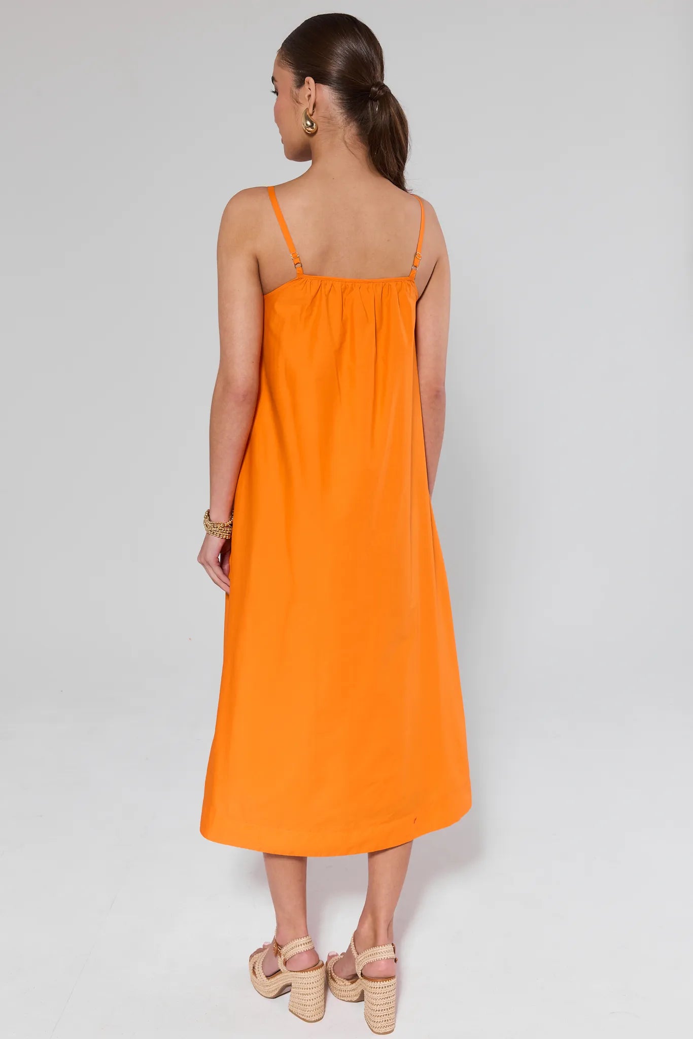 Woman wearing an Ariel Orange Shell Midi Dress on a white background