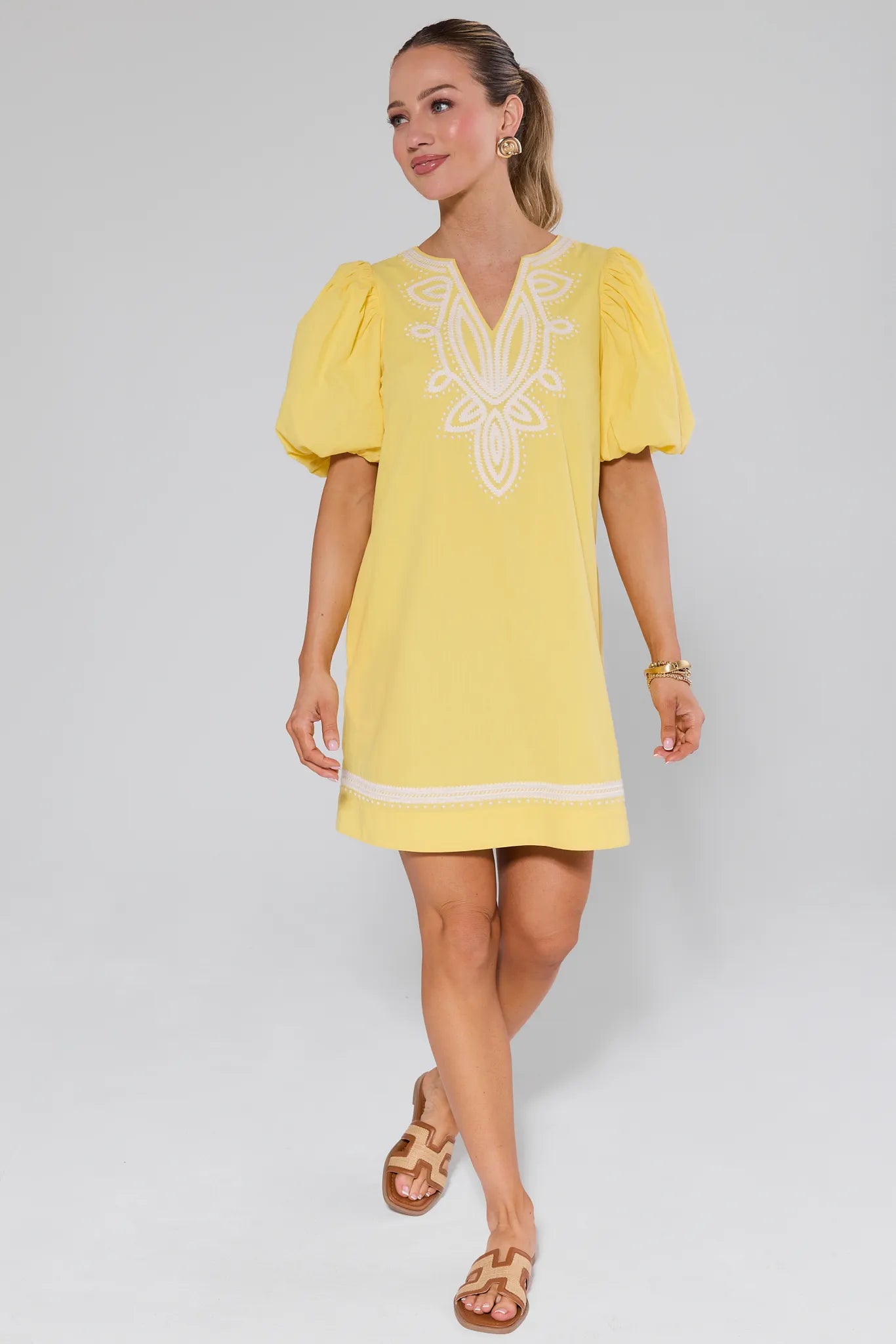 Woman wearing a yellow dress with white embroidery on a plain background Roxanne Dress Yellow
