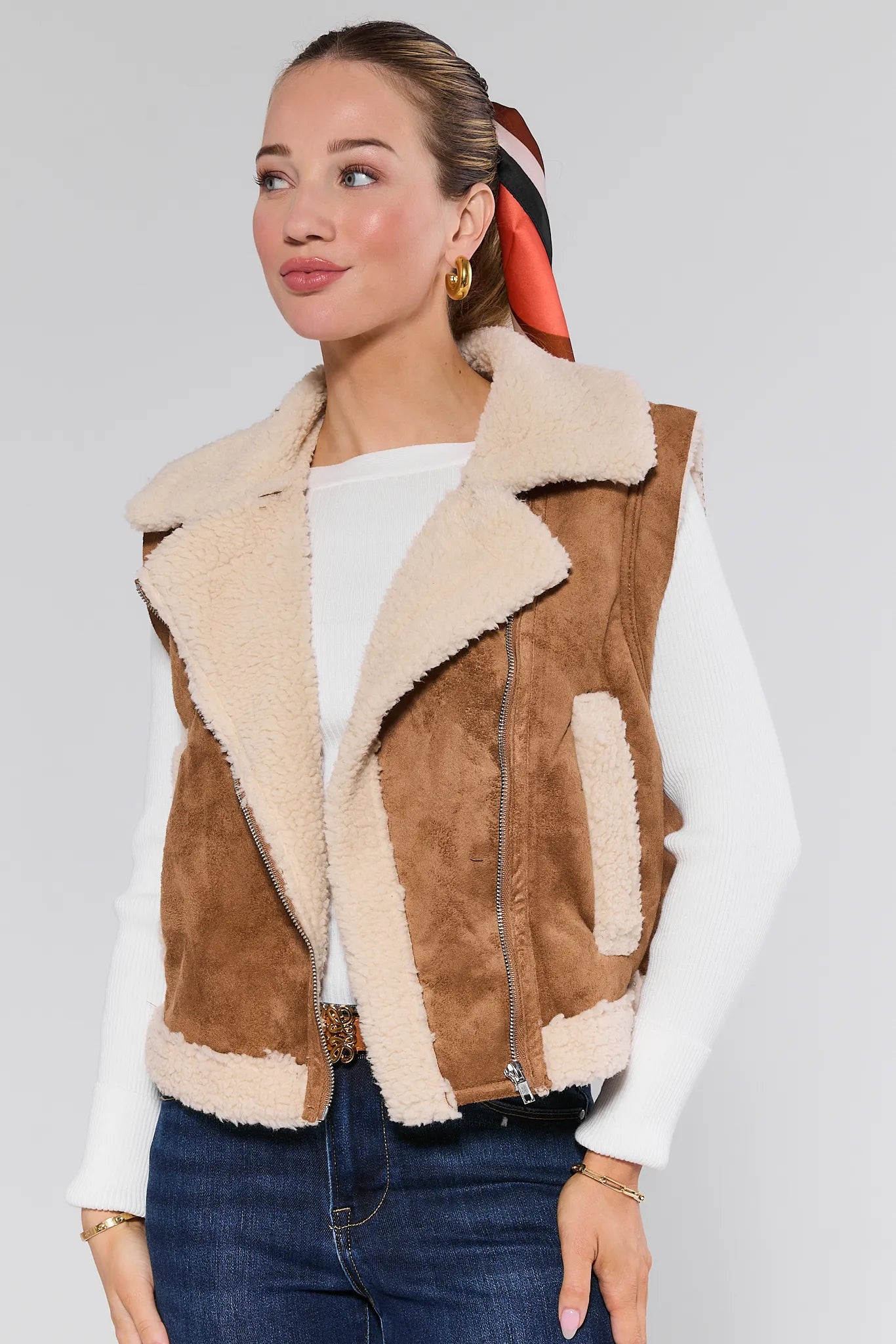 Woman wearing a brown and beige shearling Whitney Vest on a plain background