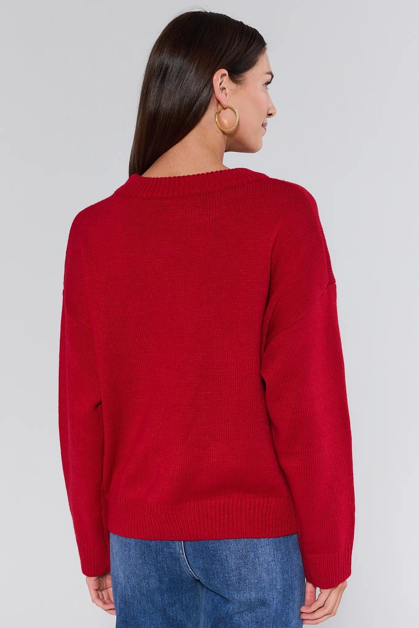 Person wearing a red sweater and blue jeans on a plain background