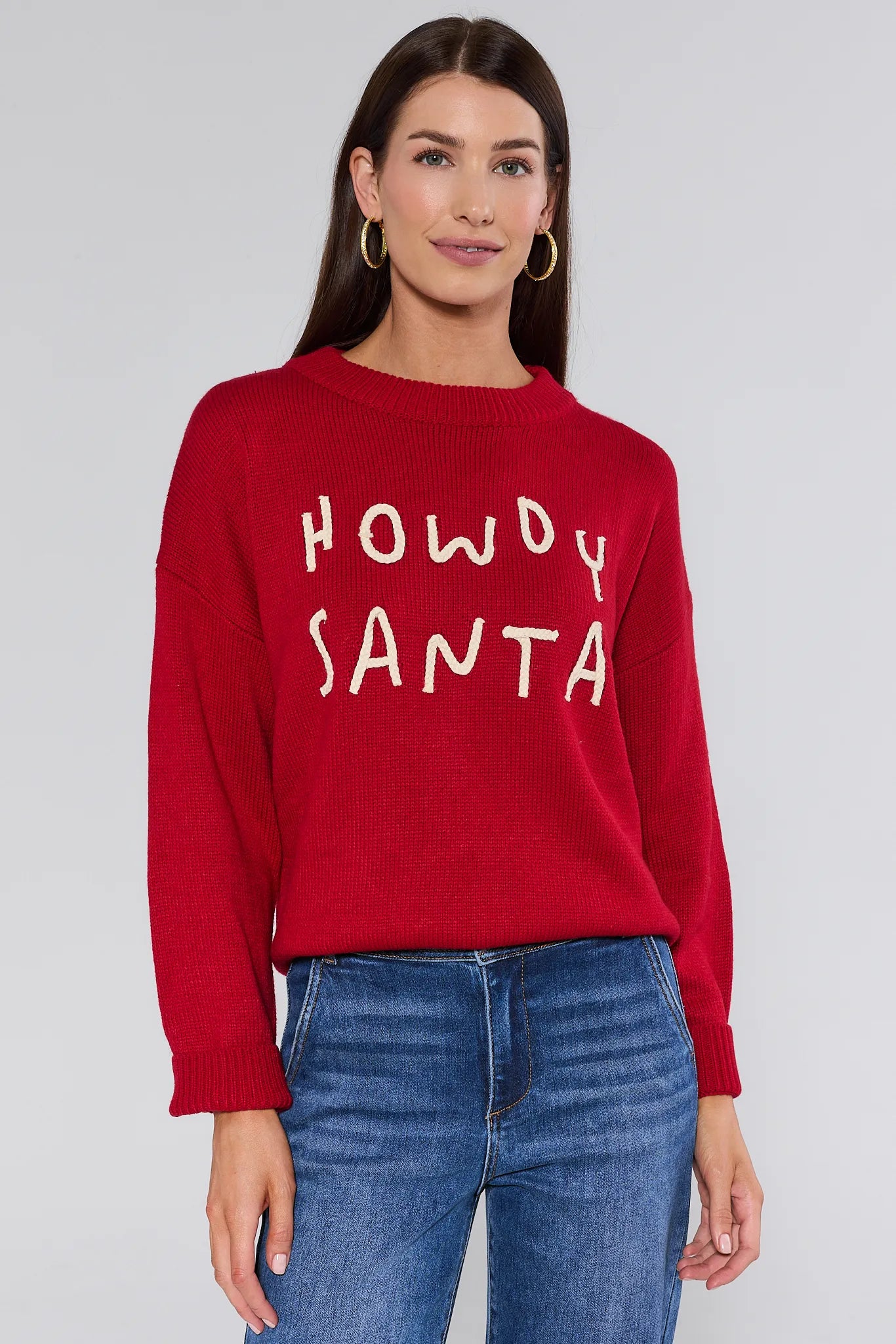 Woman wearing a red sweater with 'HOWDY SANTA' text on a plain background