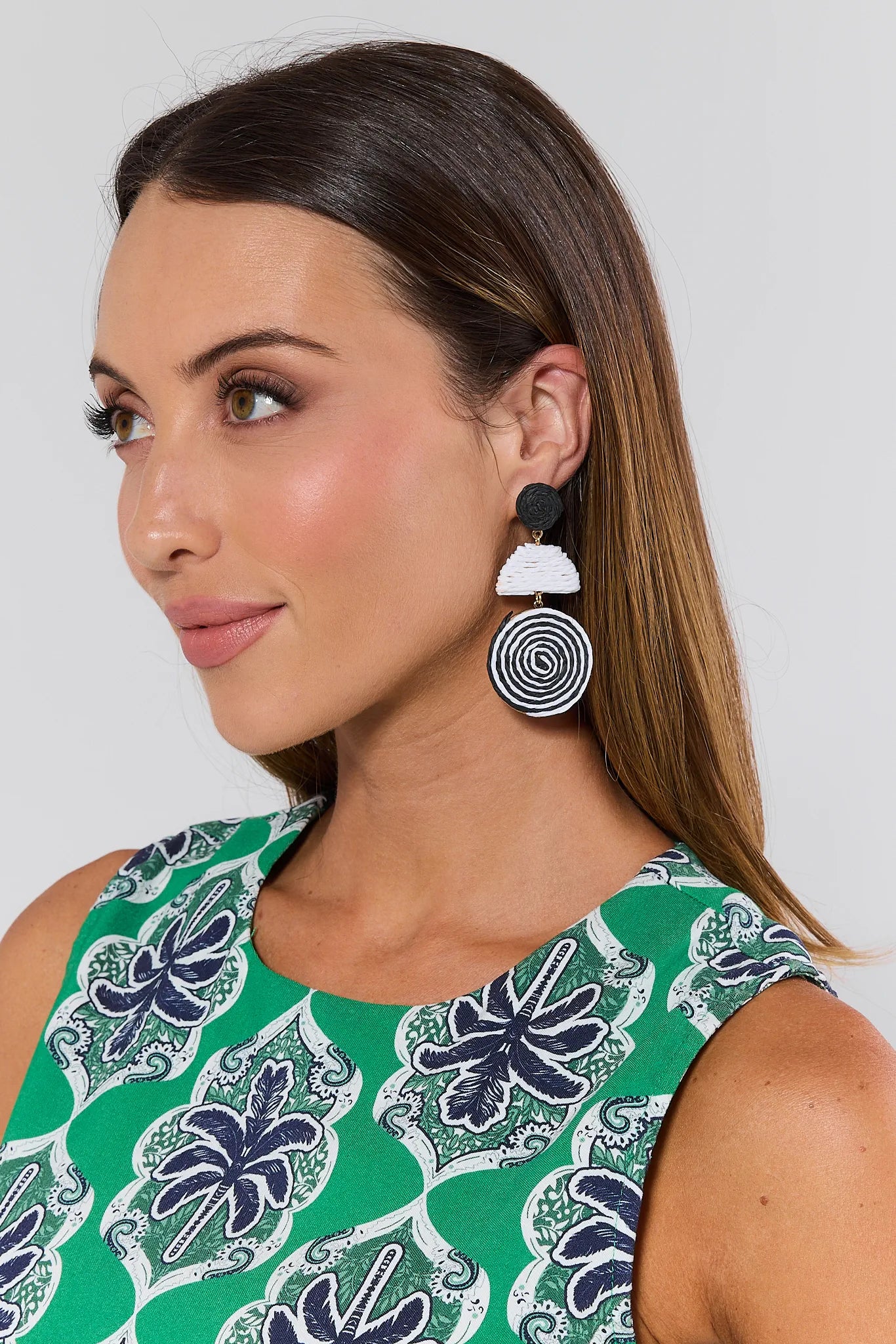 Woman wearing a green patterned top and Lynn Woven Drop Earrings with spiral design.
