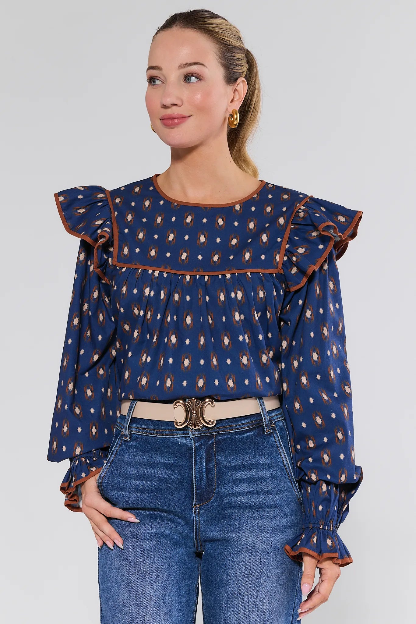 Woman wearing a blue patterned Cleo Top with ruffled sleeves against a white background