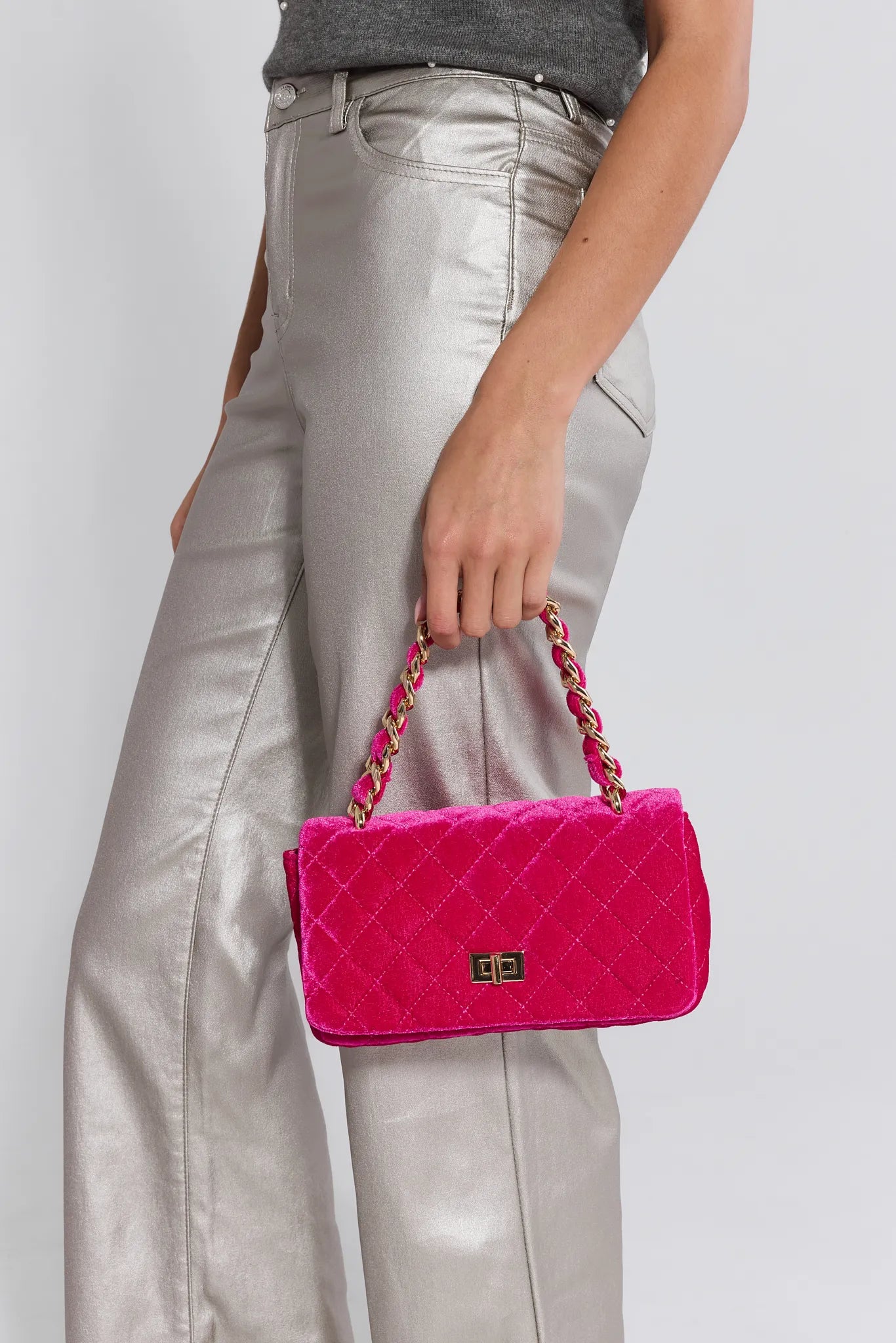 Person holding a pink quilted handbag with a white background