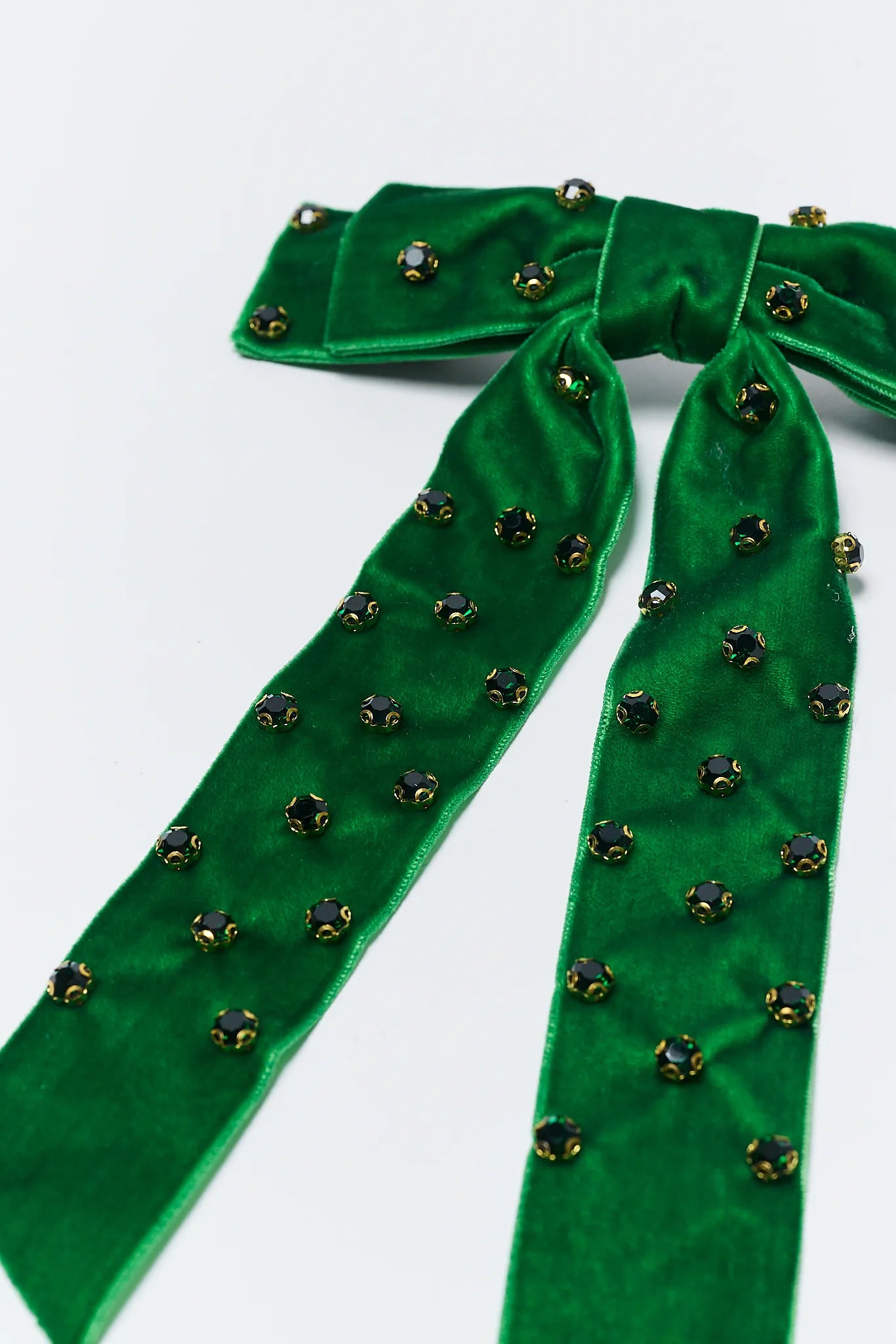 Green velvet ribbon with decorative beads on a white background