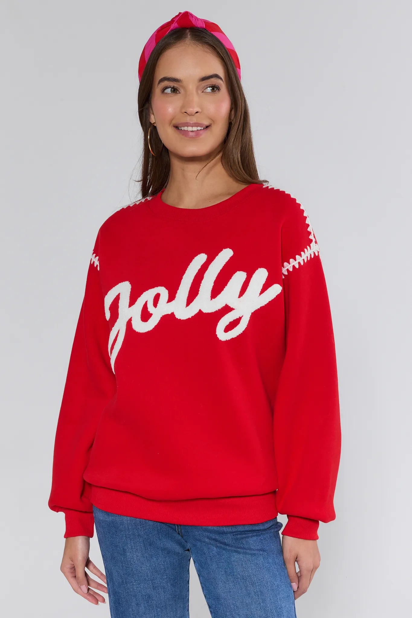 Woman wearing a red sweater with 'Jolly' text on a plain background