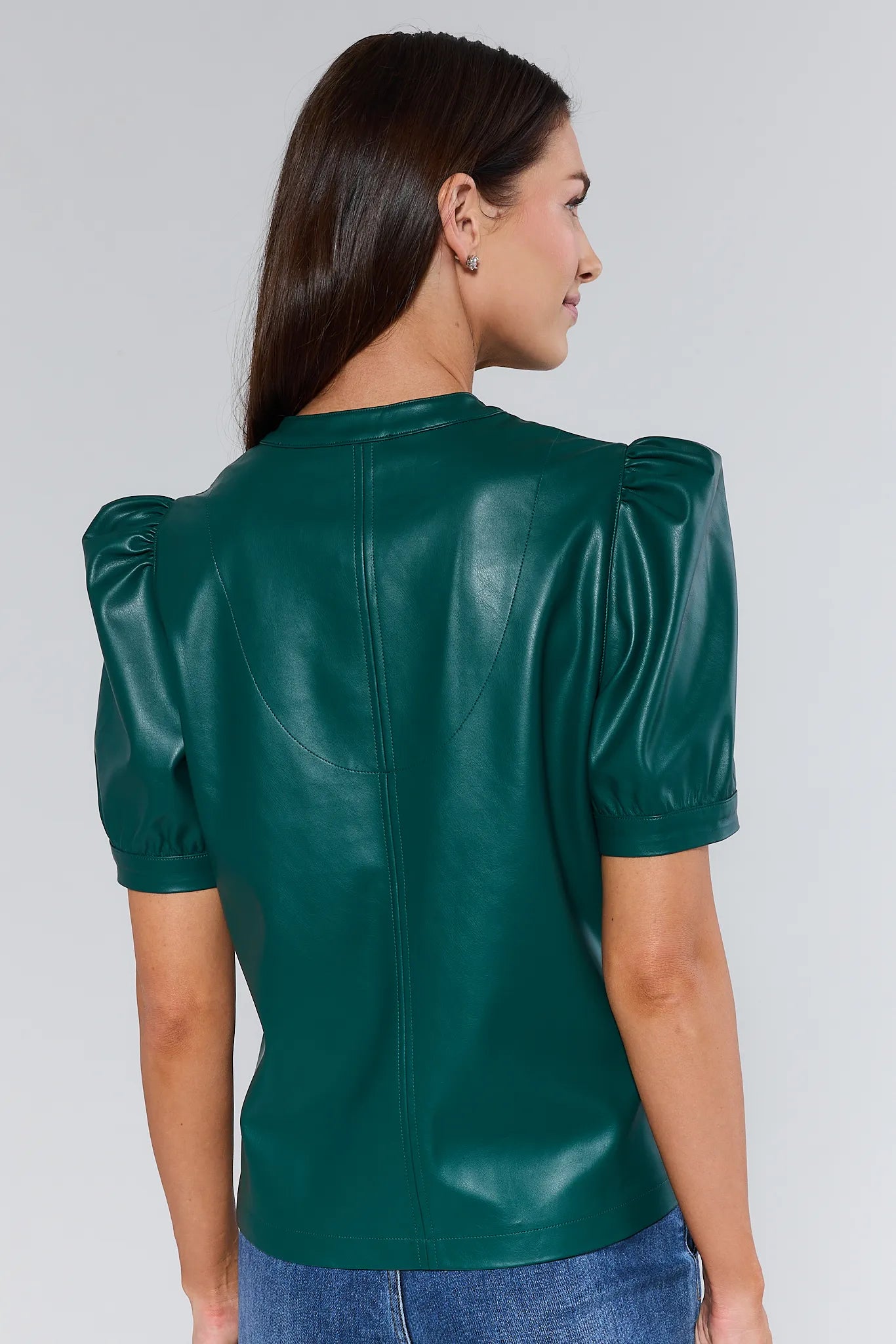 Woman wearing a green Ariana Top with puff sleeves against a plain background