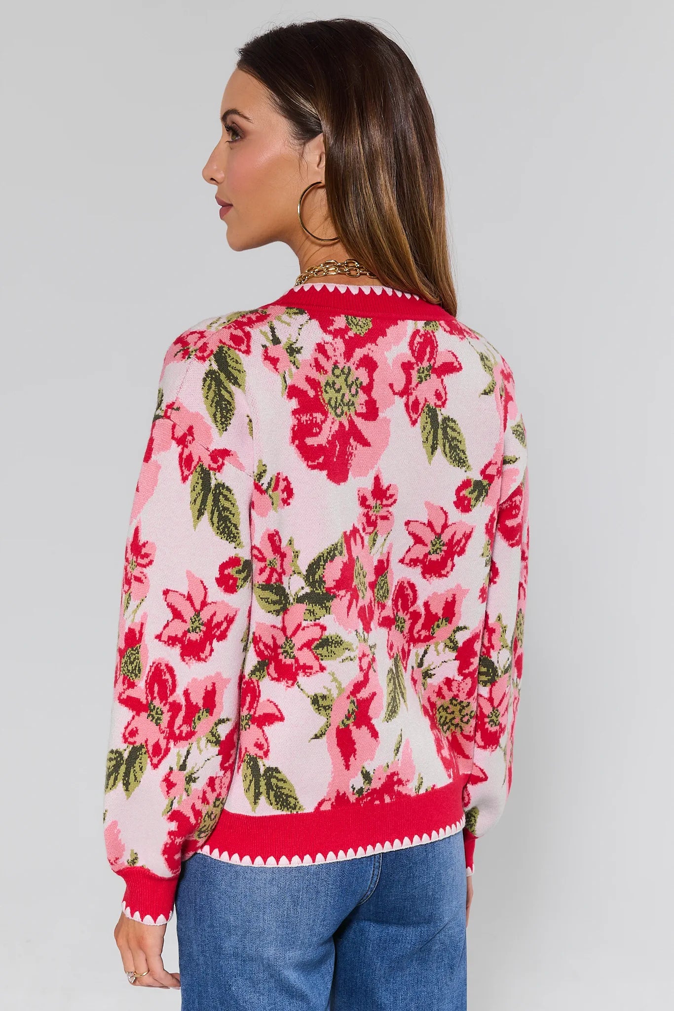 Woman wearing a floral cardigan with pink flowers on a plain background