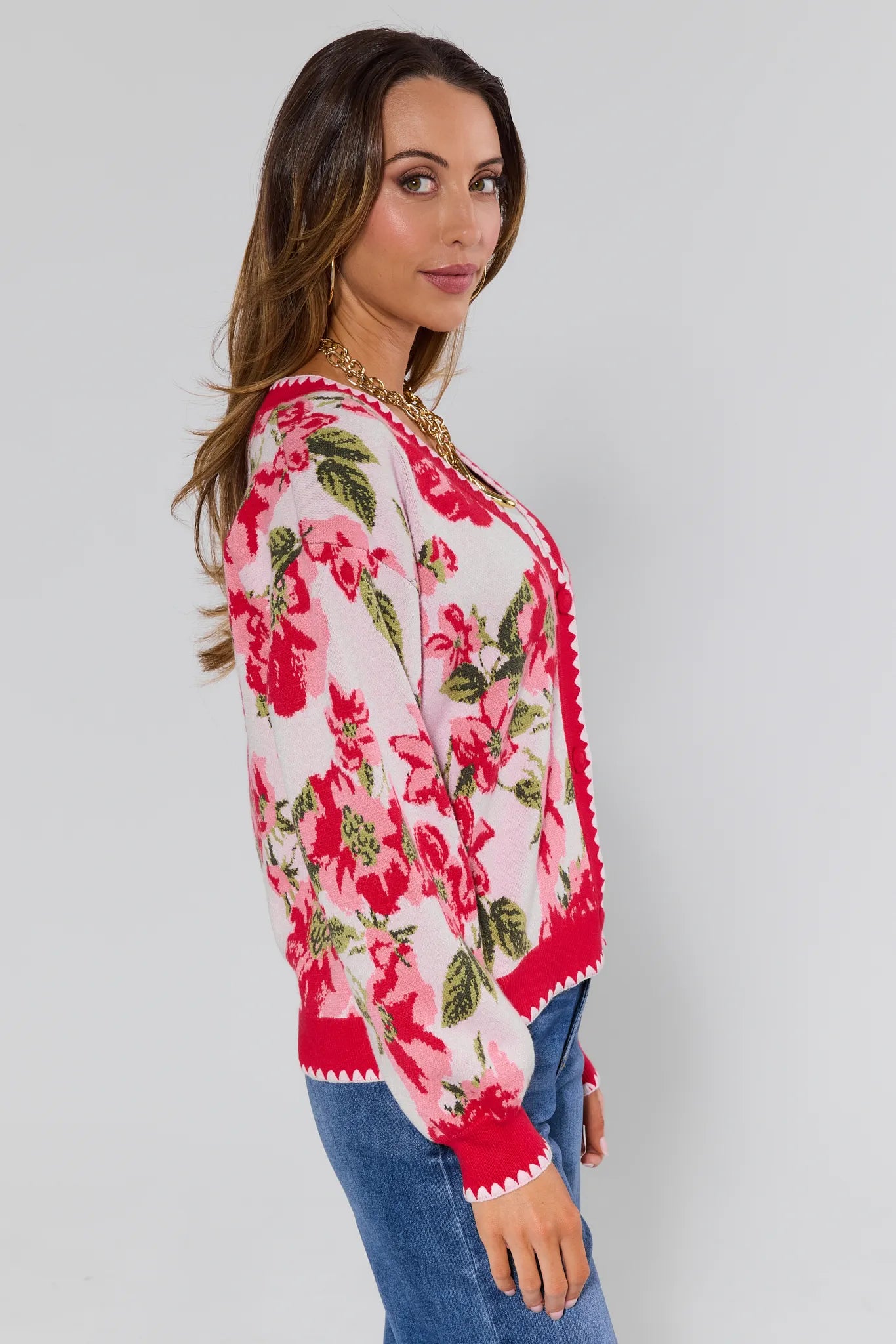 Woman wearing a floral sweater with red trim on a plain background