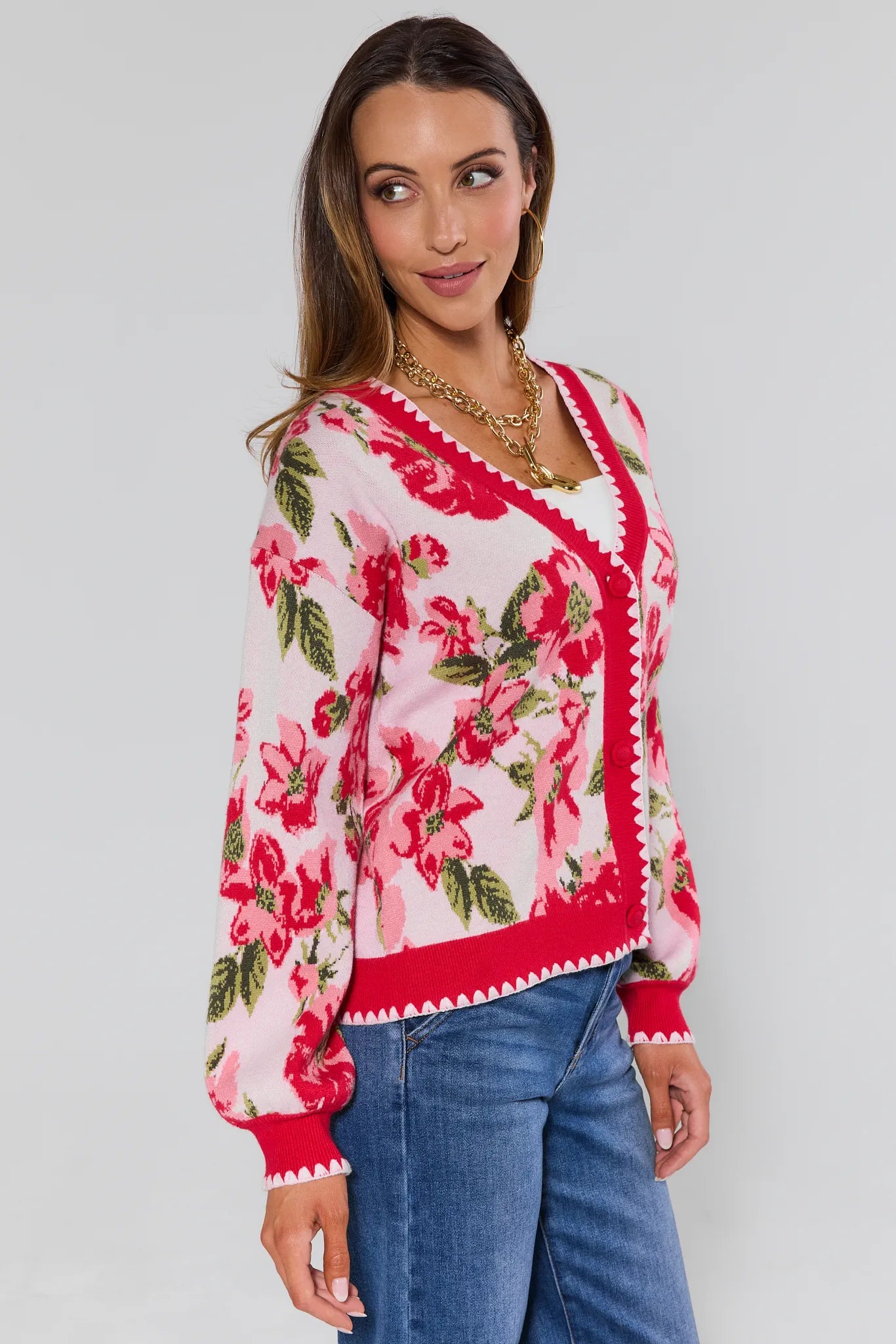 Woman wearing a floral blouse with red and pink flowers on a plain background