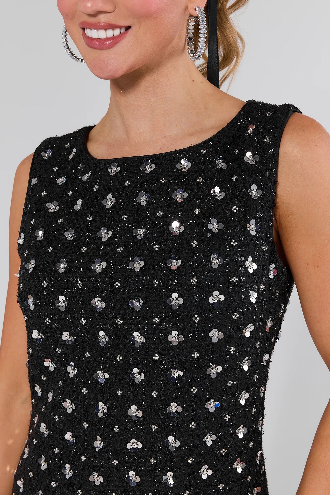 Woman wearing a Jude Black Embellished Mini Dress with white floral pattern against a plain background