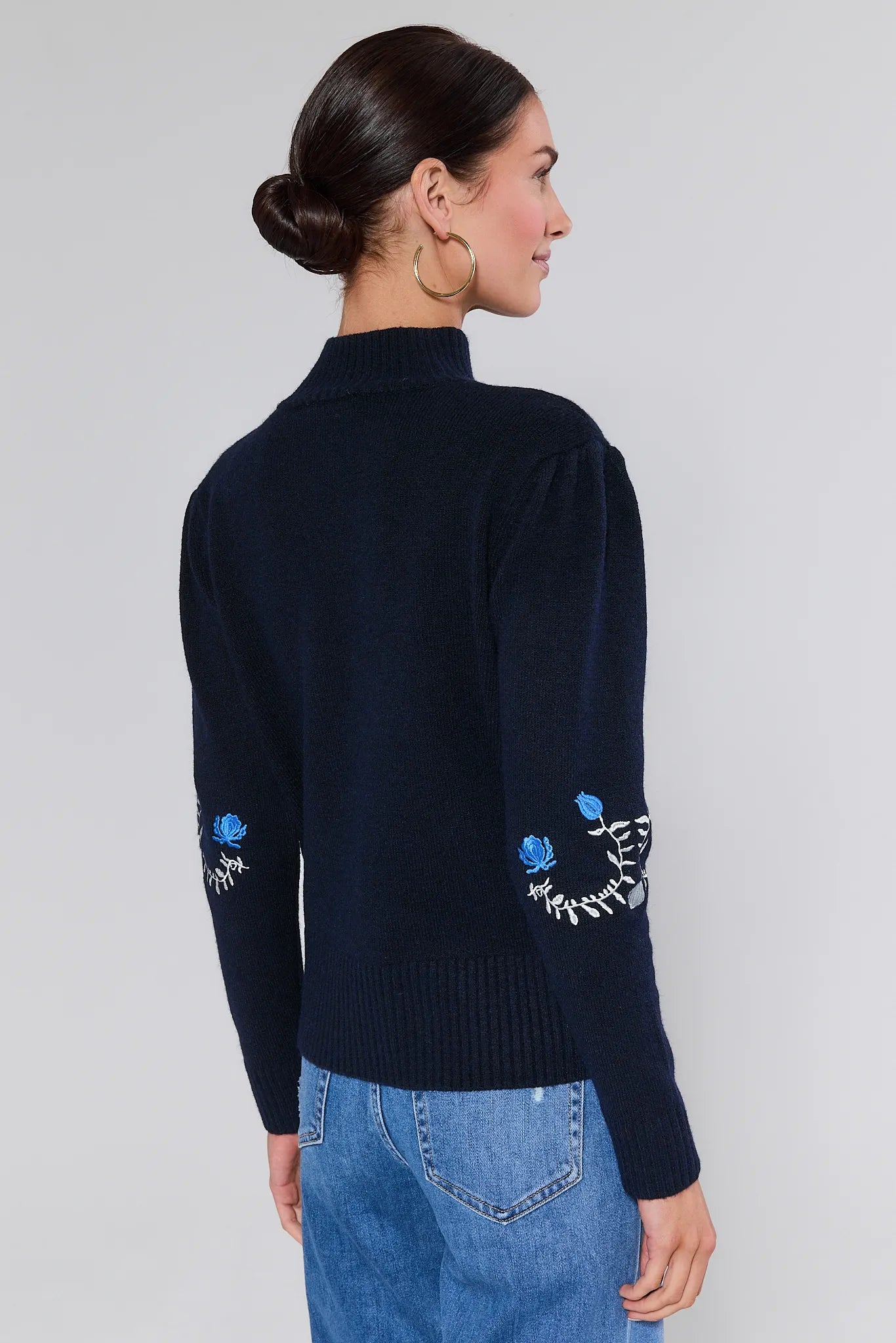 Woman wearing a Celia Blue Embroidered Knit Sweater with floral embroidery on a plain background