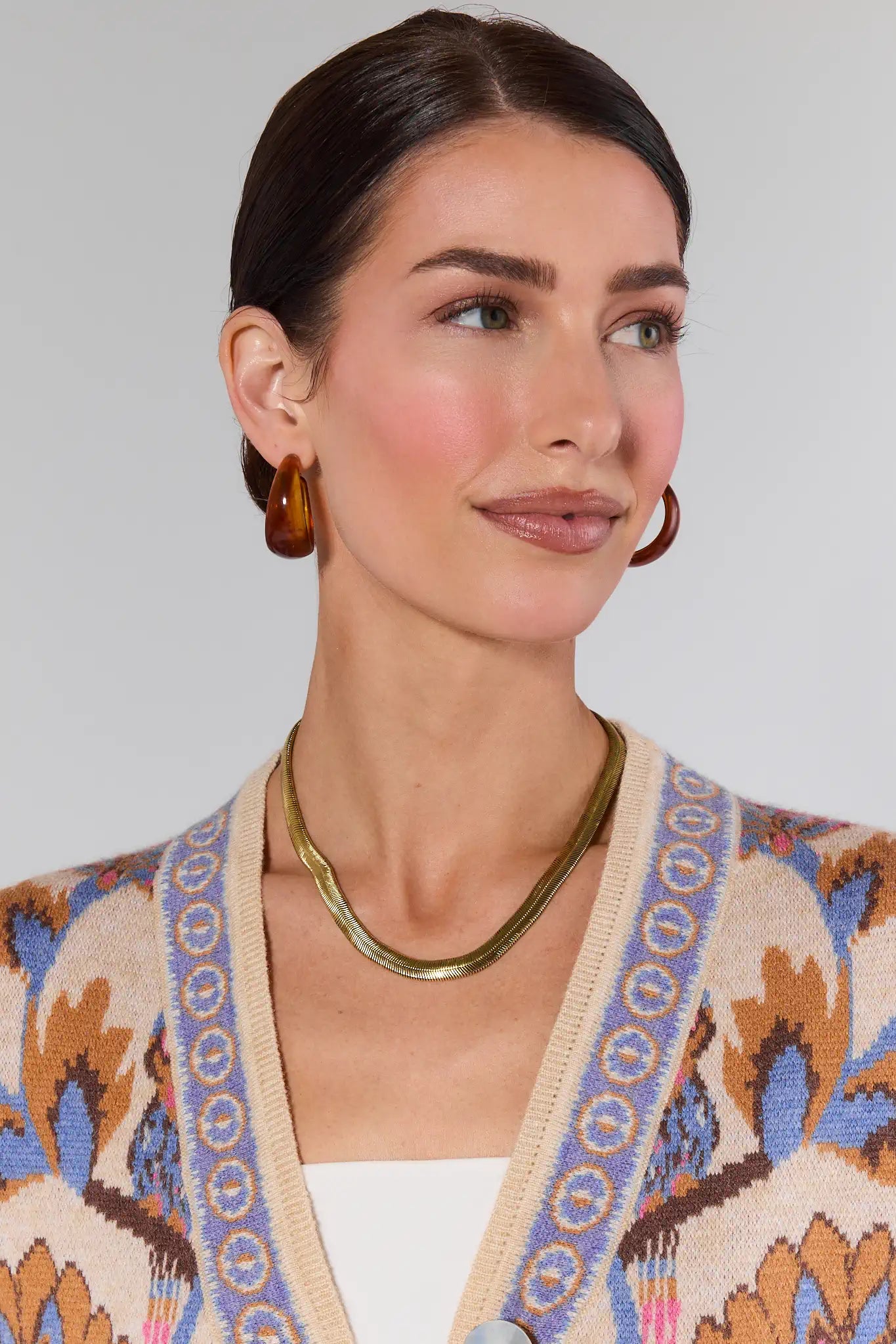 Woman wearing a patterned cardigan with a plain background Irene Gold Snake Chain Necklace