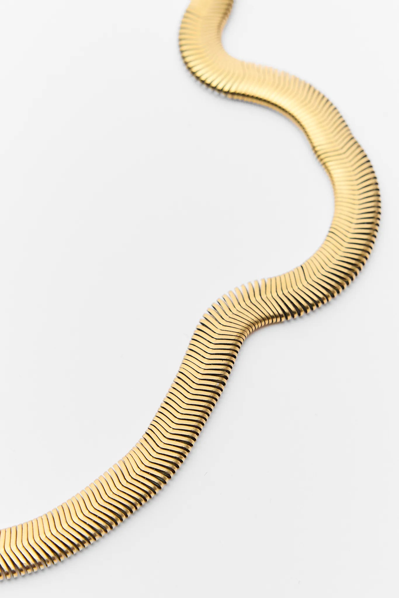 Gold necklace with wavy design on a white background Irene Gold Snake Chain Necklace