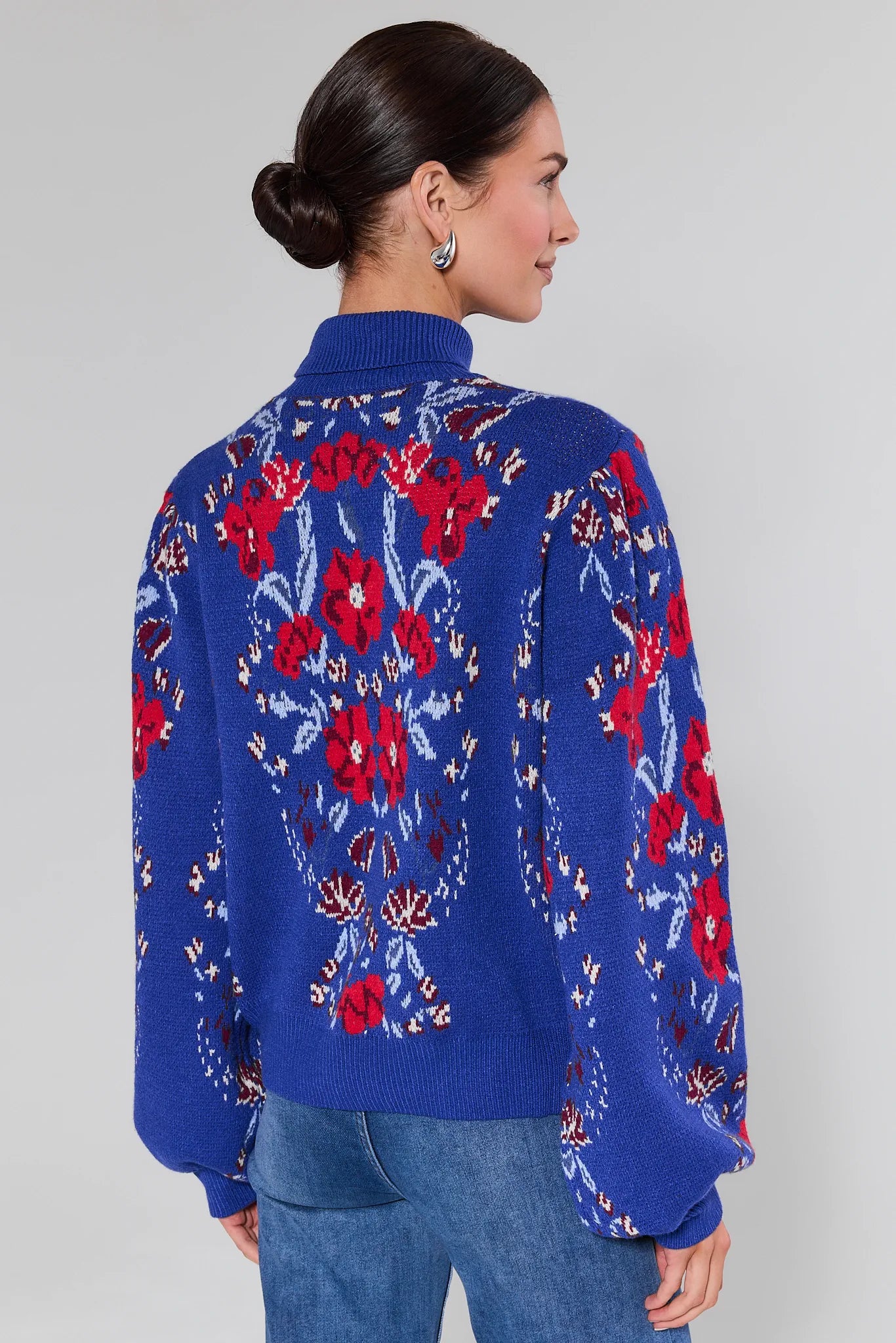 Woman wearing a Loretta Blue Floral Knit Sweater on a plain background