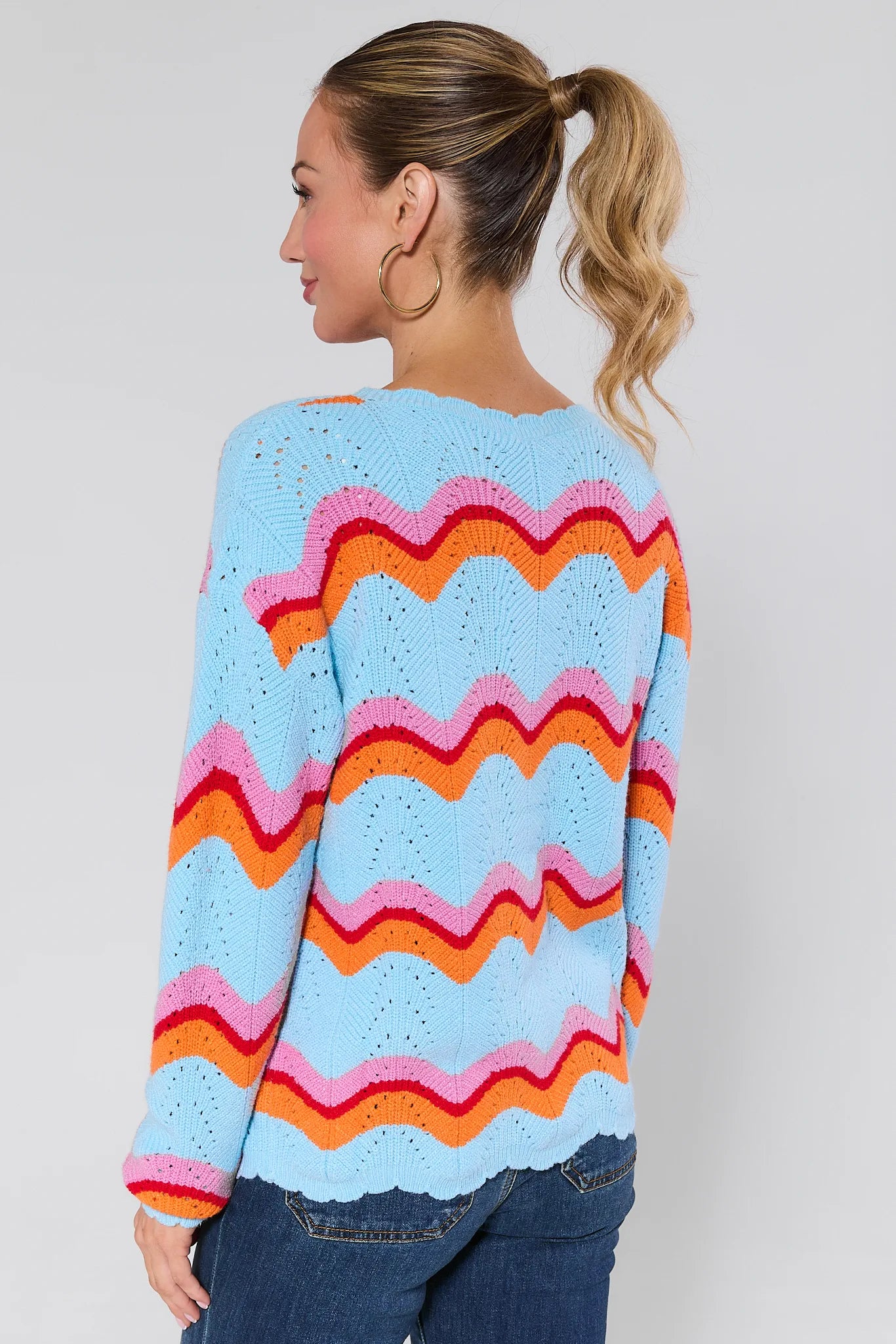 Person wearing a Alice Multi Striped Scallop Sweater with a plain background