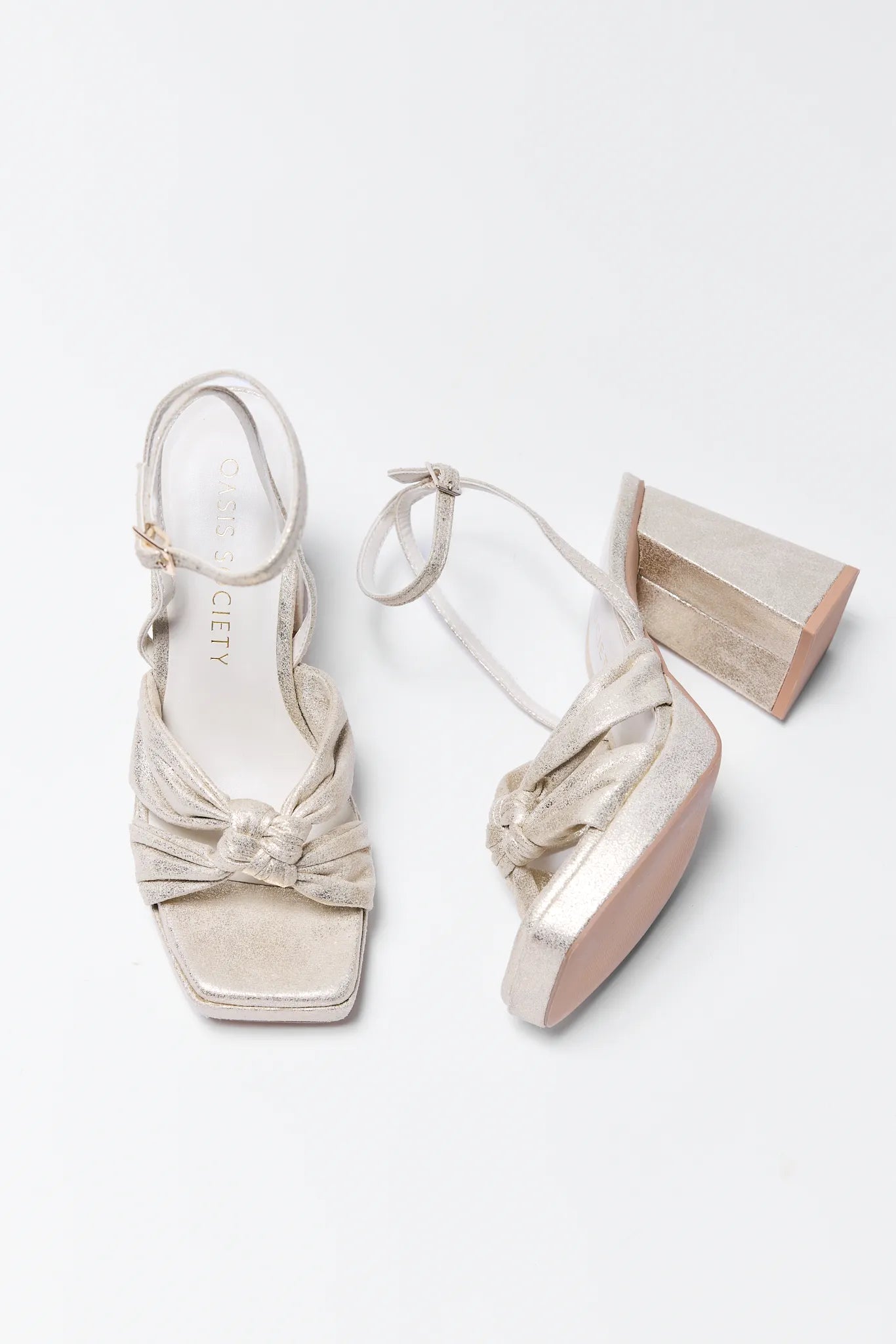 Pair of Zoey Gold Platform Heels with bow details on a white background