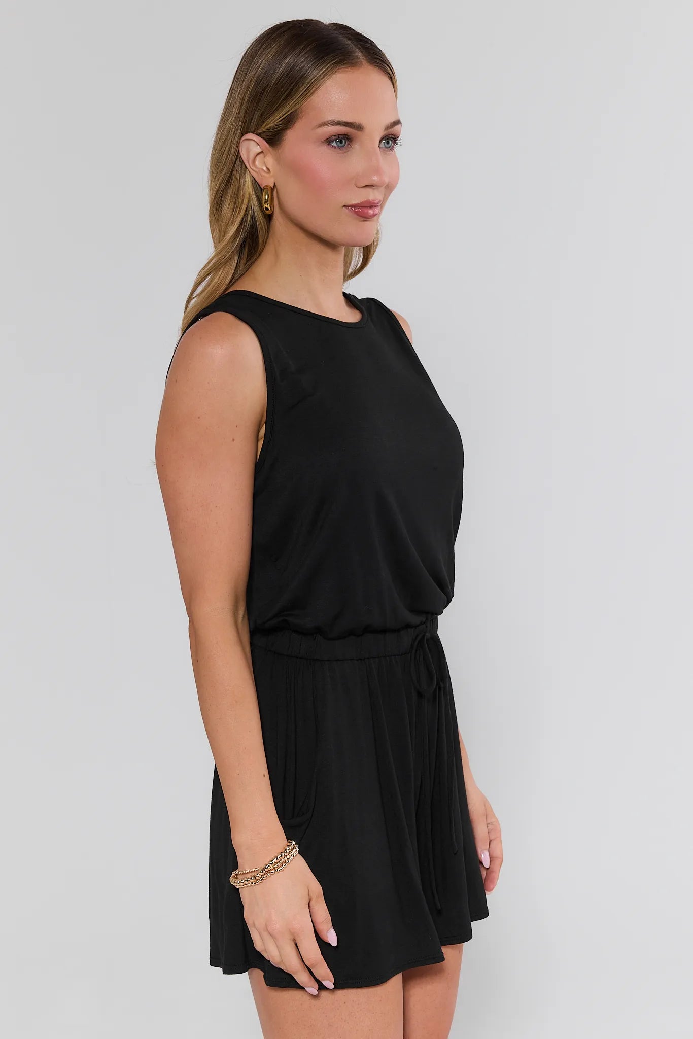 Woman wearing a black sleeveless dress against a plain background