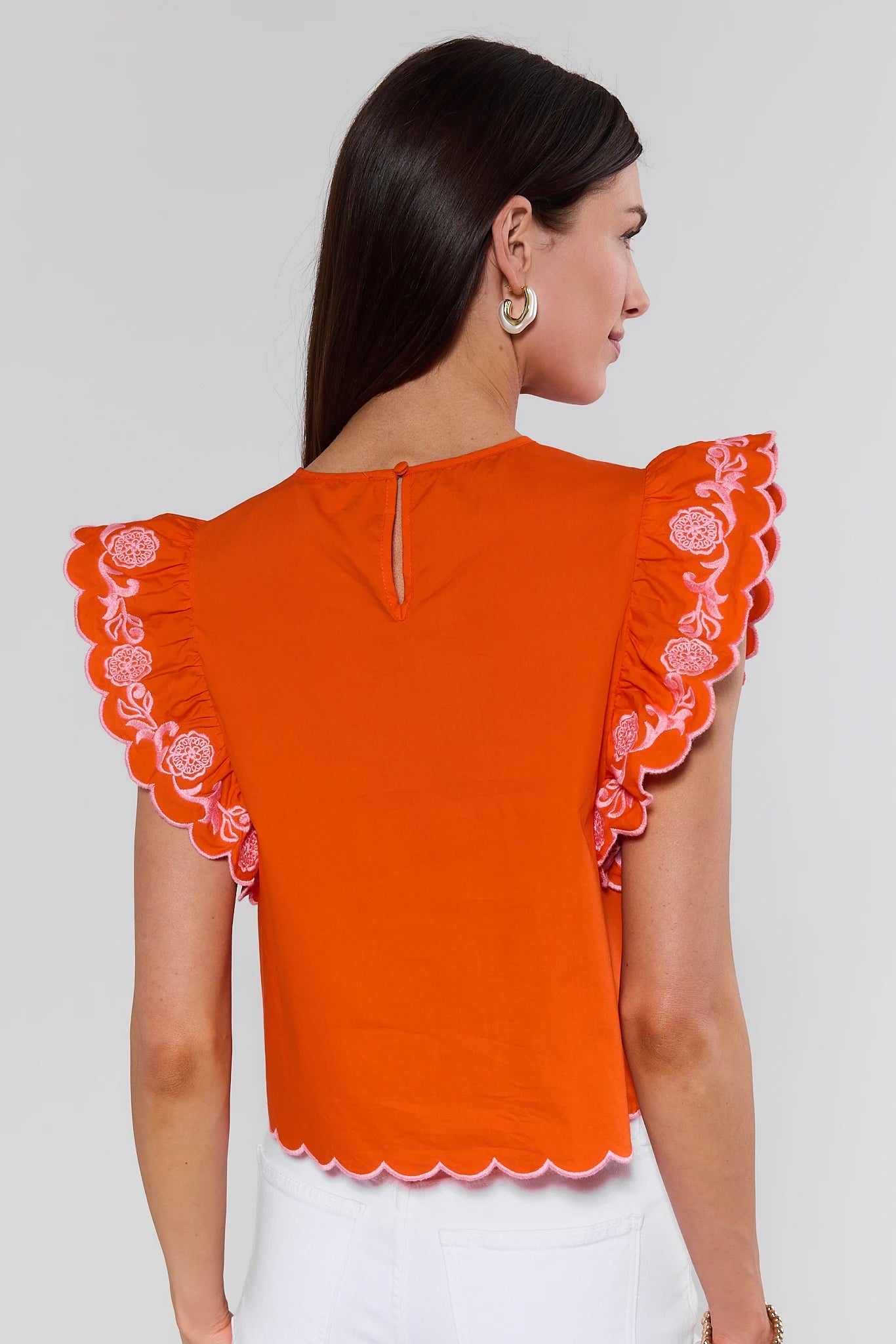 Orange top with floral lace details on a plain background