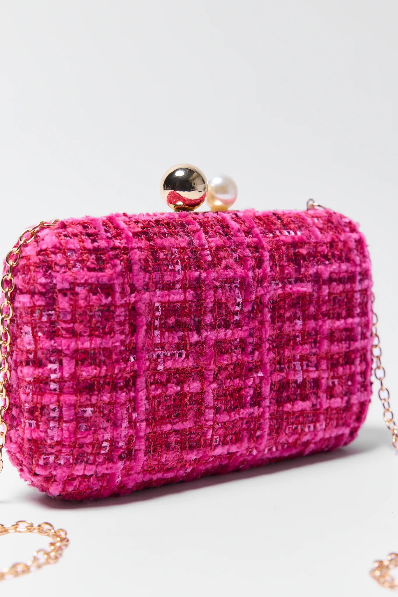 Pink tweed Mabel clutch bag with gold chain on a light gray background