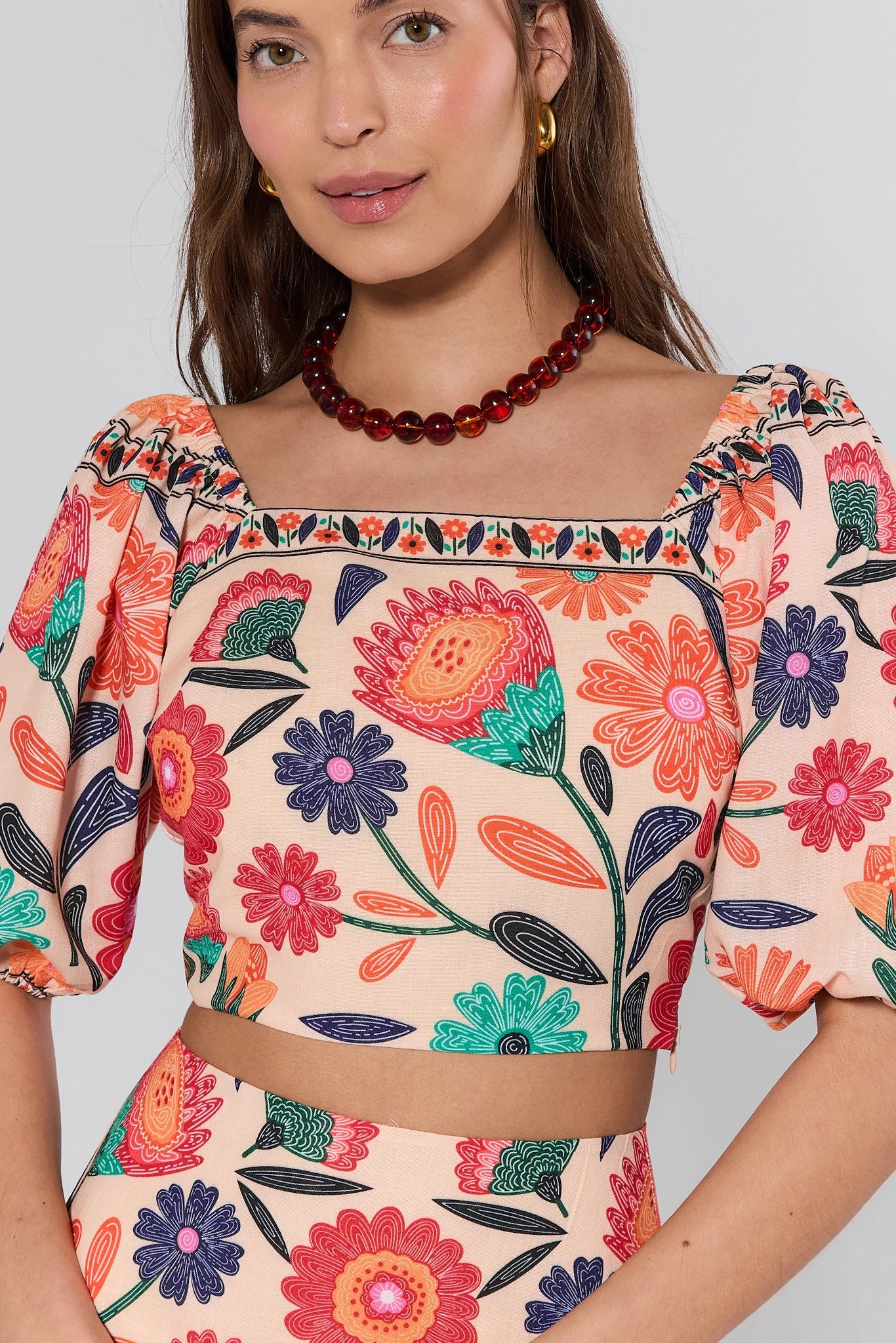 Woman wearing a colorful floral top against a plain background