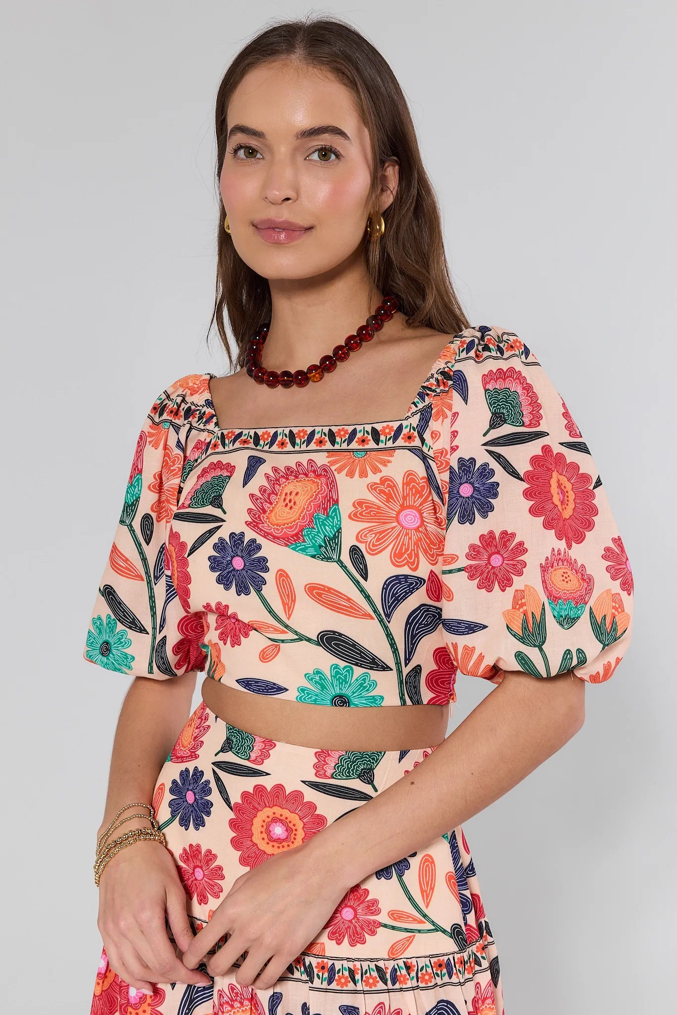 Woman wearing a colorful floral dress on a plain background