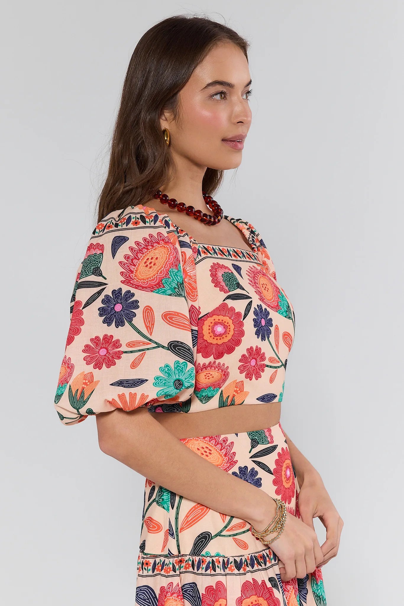 Woman wearing a colorful floral two-piece outfit on a plain background