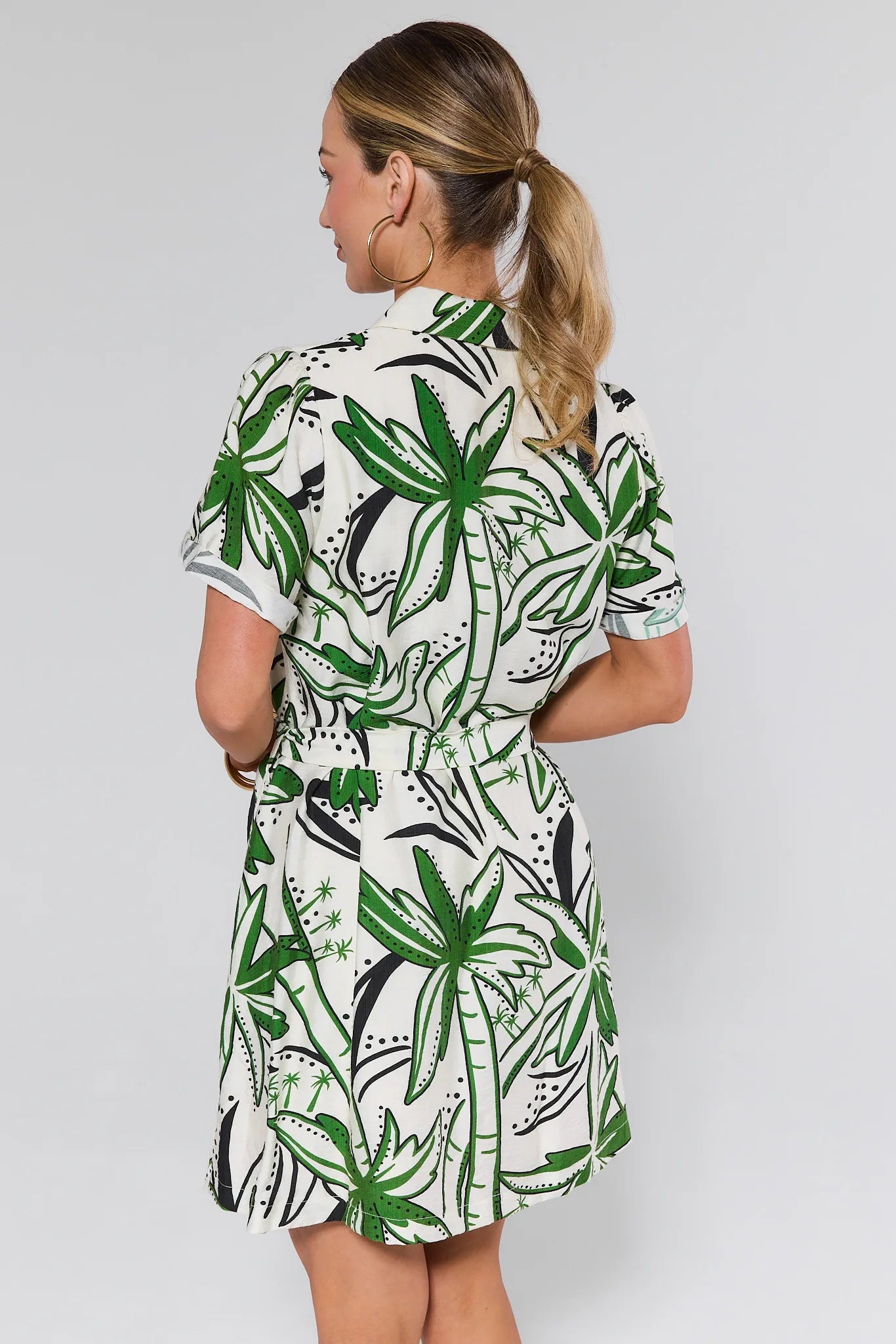 Woman wearing a white dress with green leaf against a white background