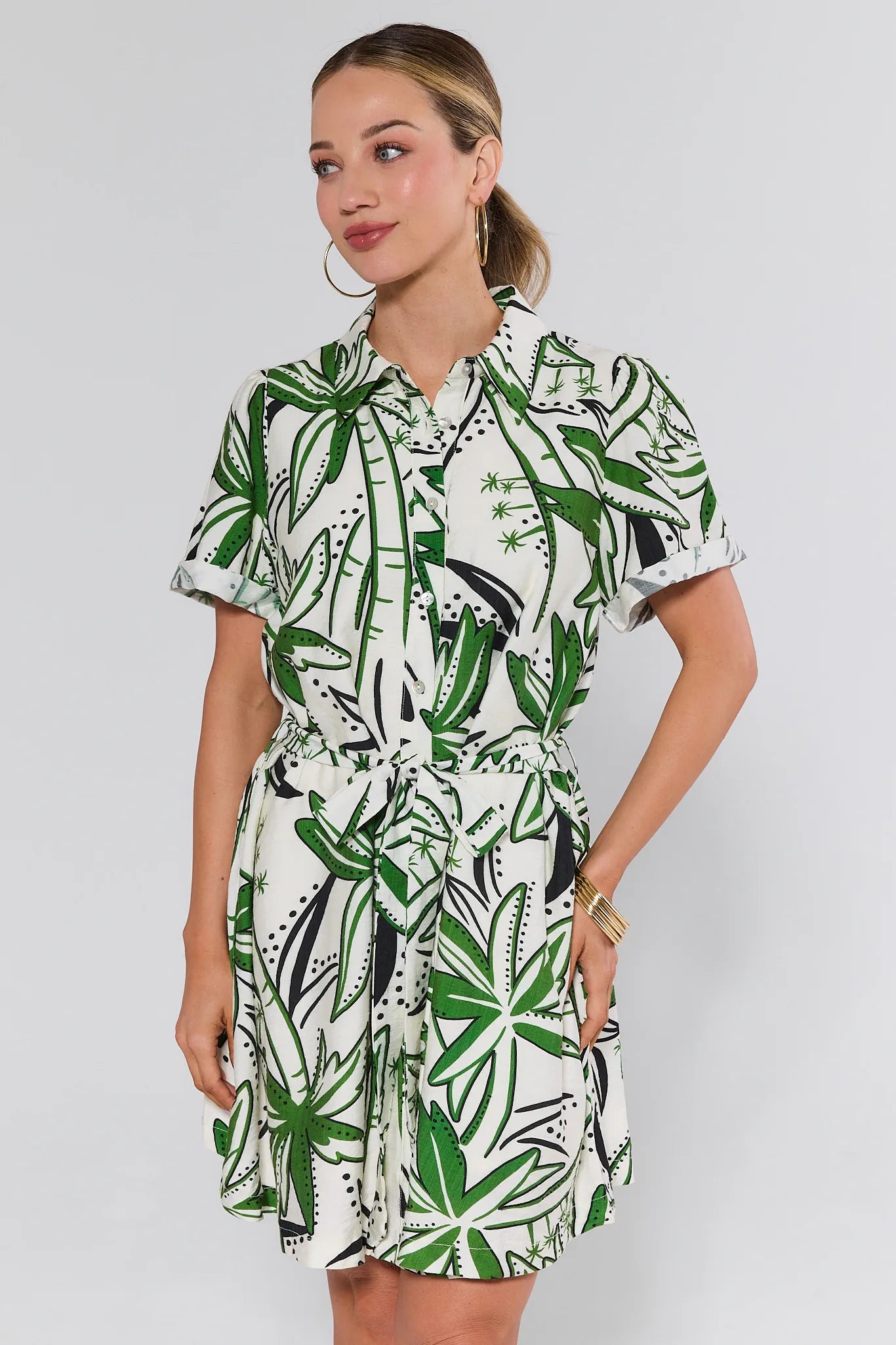 Woman wearing a green and white patterned dress on a plain background