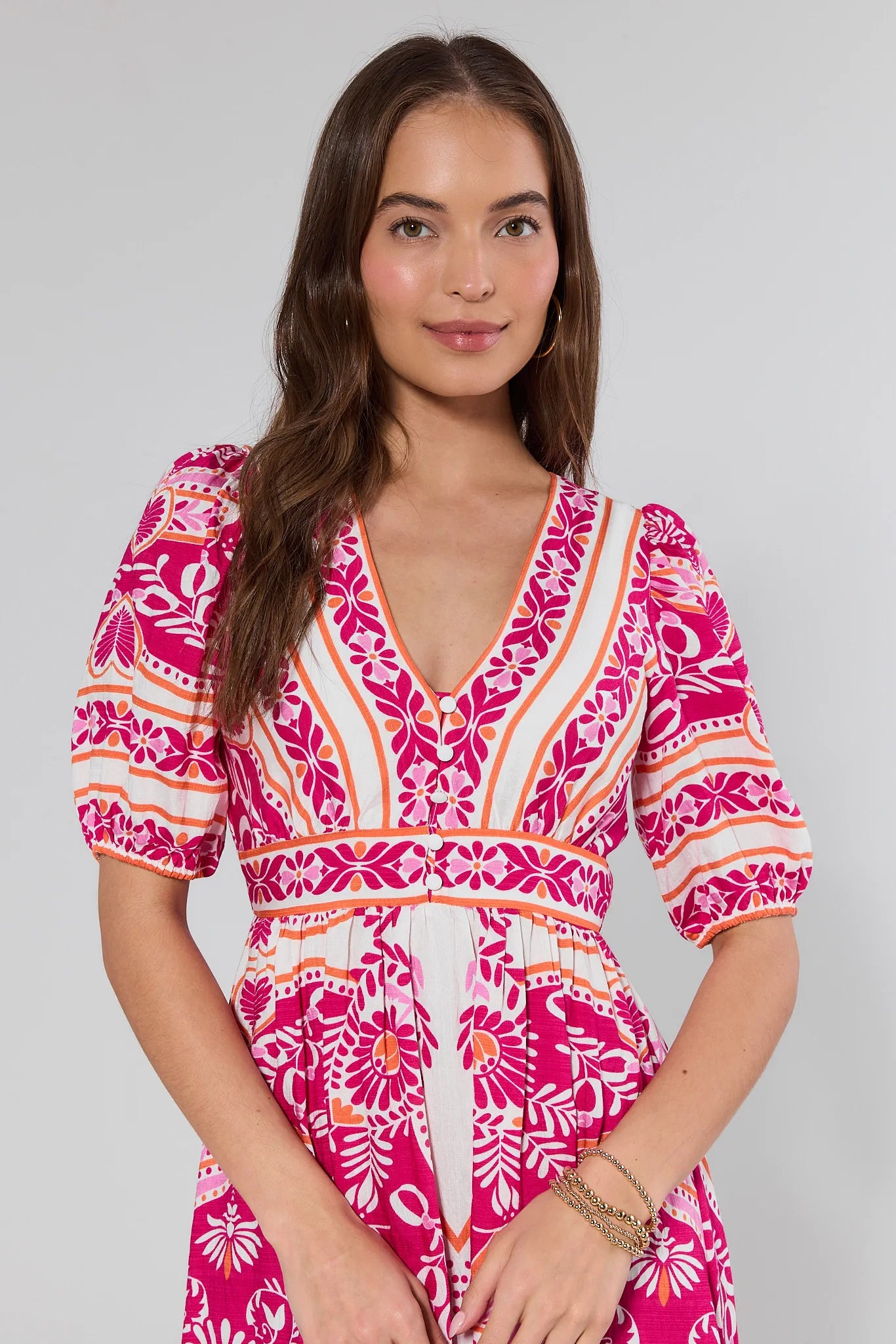 Woman wearing a pink and white patterned dress on a gray background