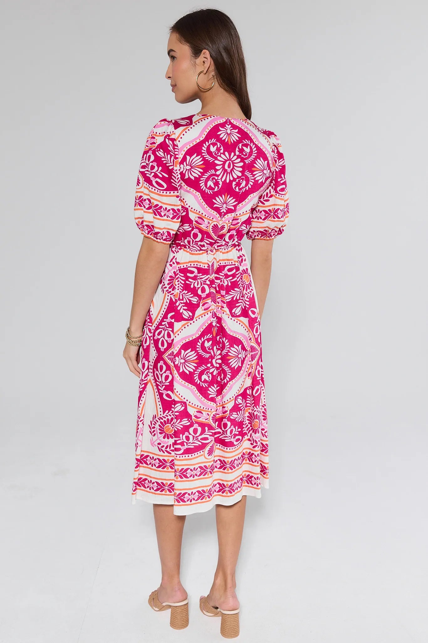 Woman wearing a pink patterned dress on a gray background